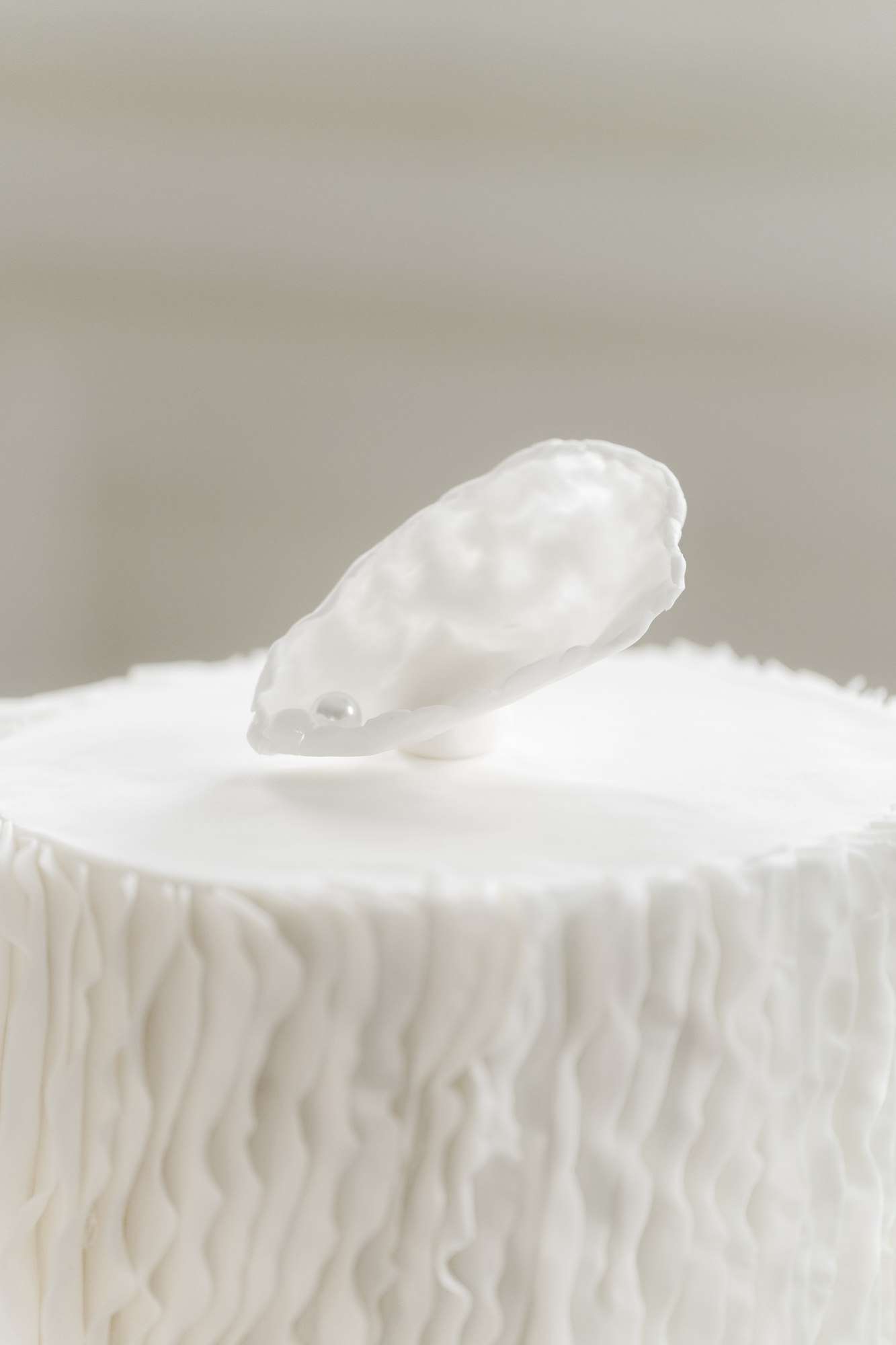 White wedding cake topper with porcelain bird on textured buttercream cake against neutral background