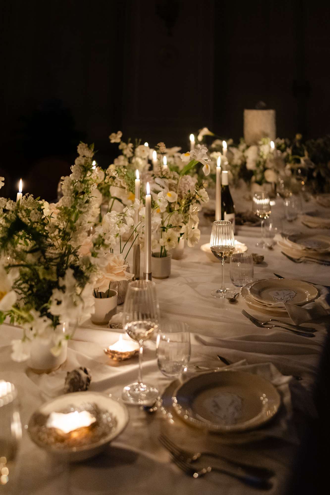 Evening reception table with white stock and rose centerpieces, silver candlesticks, and candlelit glassware