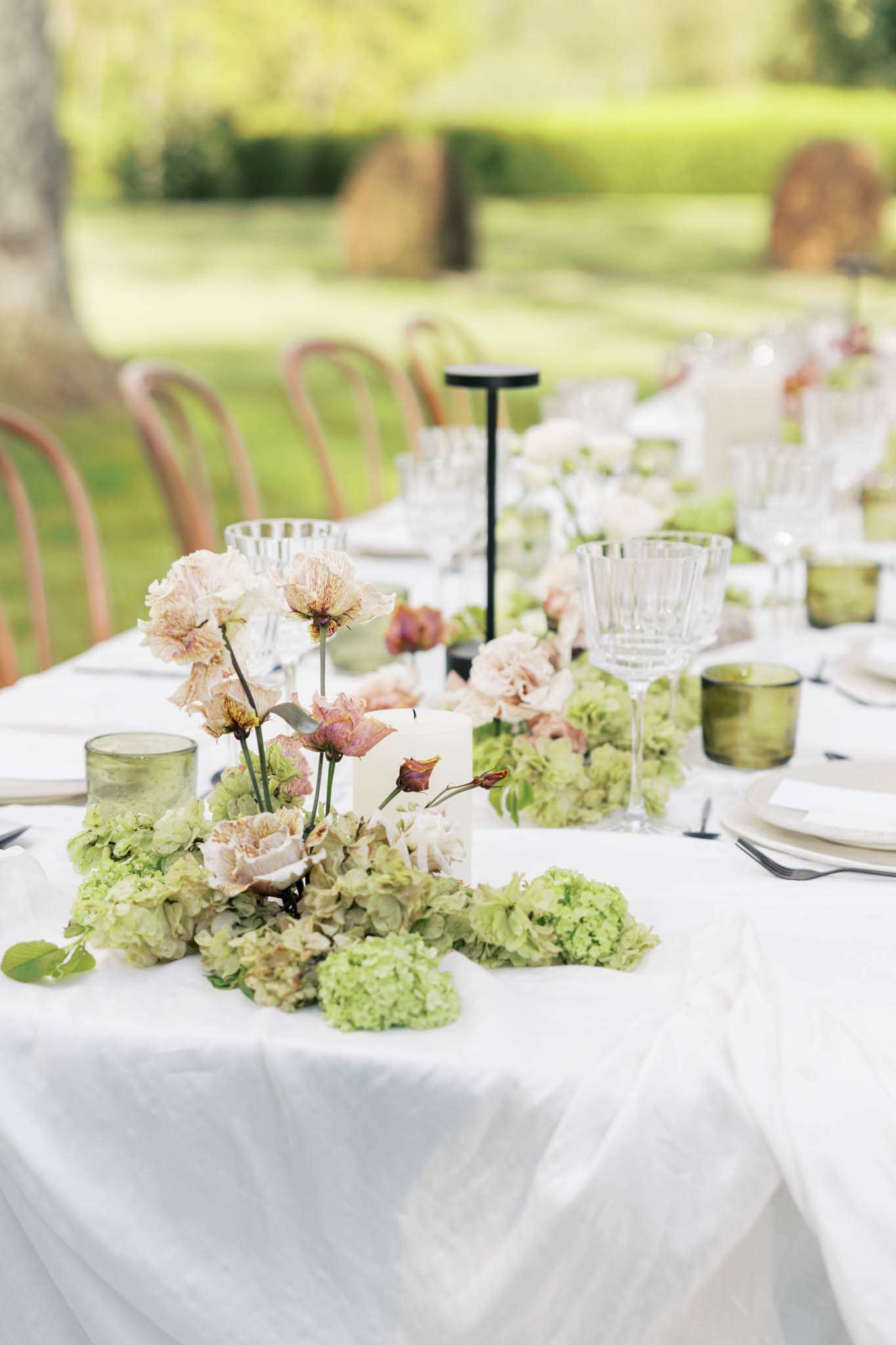 Wedding reception table with chartreuse hydrangeas, blush orchids, crystal glasses, and black taper candles