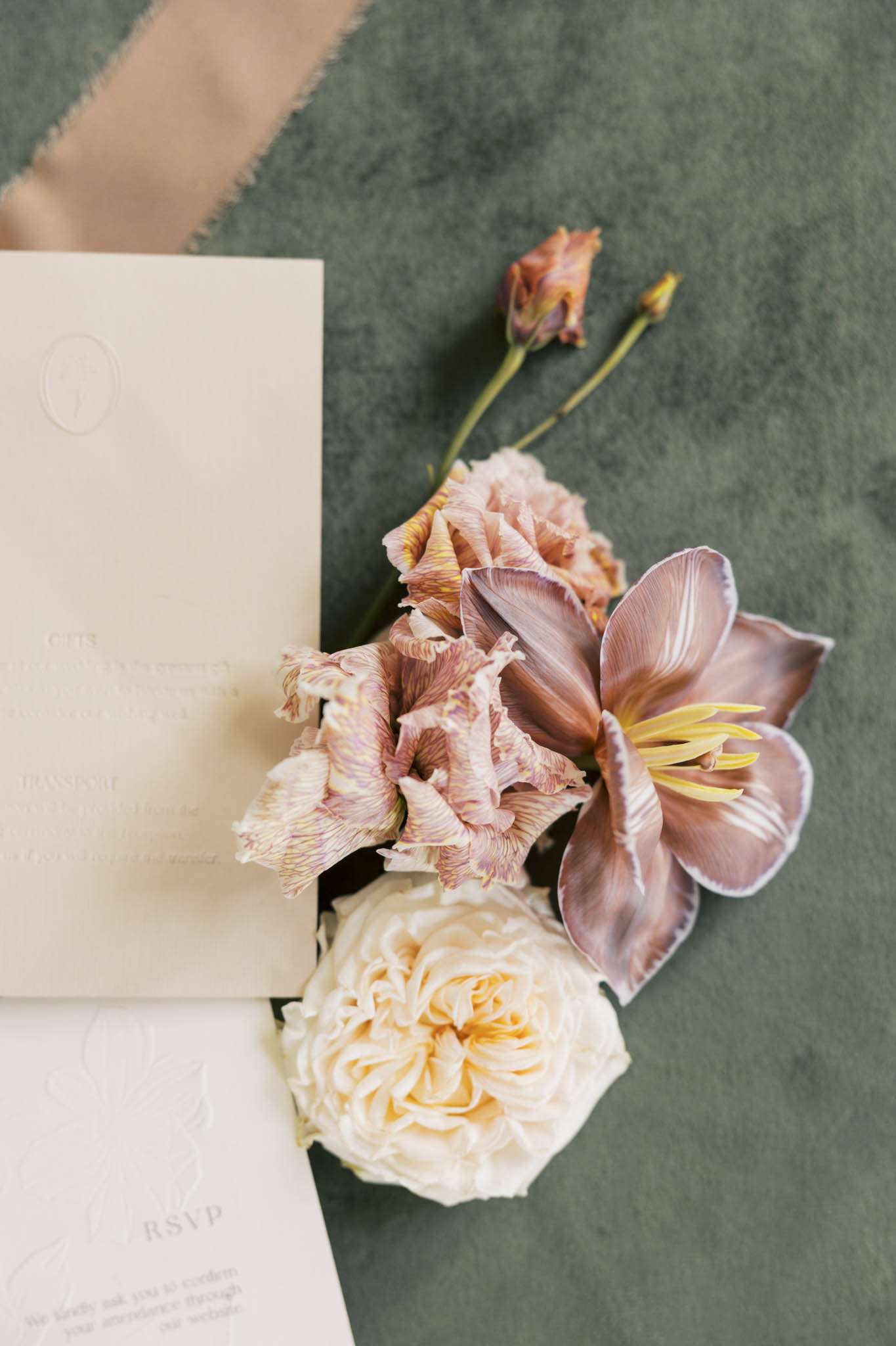 Cream invitation suite with wax seal, mauve lisianthus, and garden rose on sage velvet surface