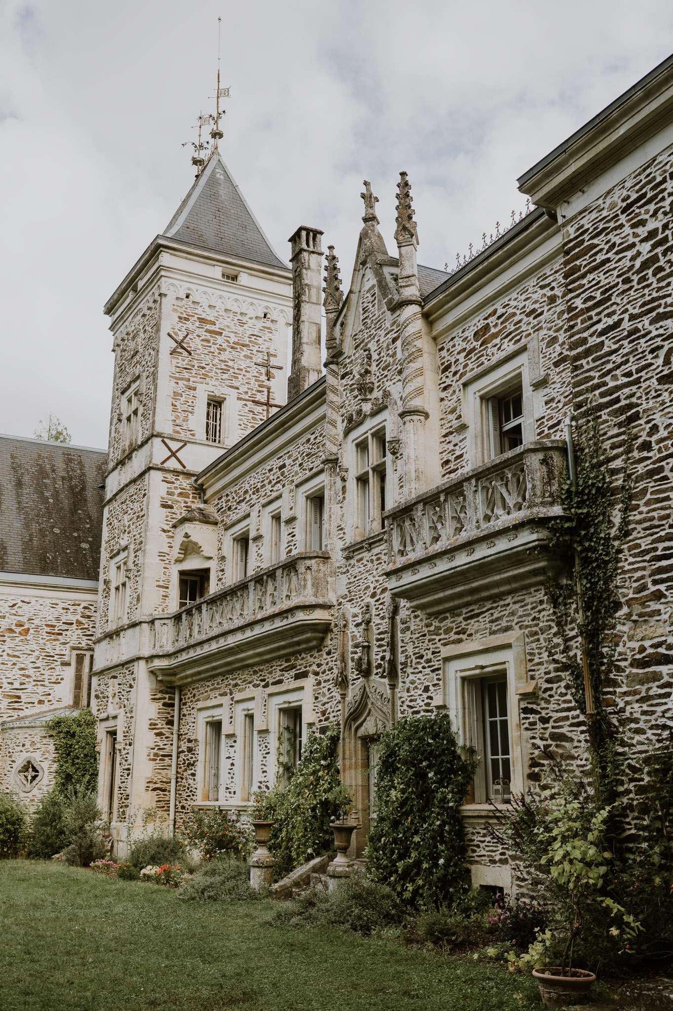 Gothic chateau facade with granite towers, carved pinnacles, carved balustrades, and climbing ivy