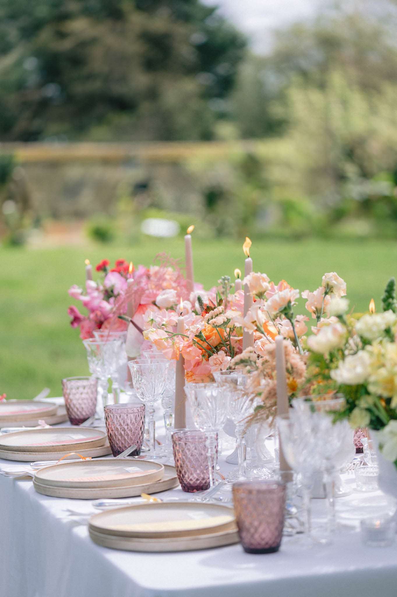 Reception table with ombre floral runner from magenta to peach to yellow with pressed glass tumblers