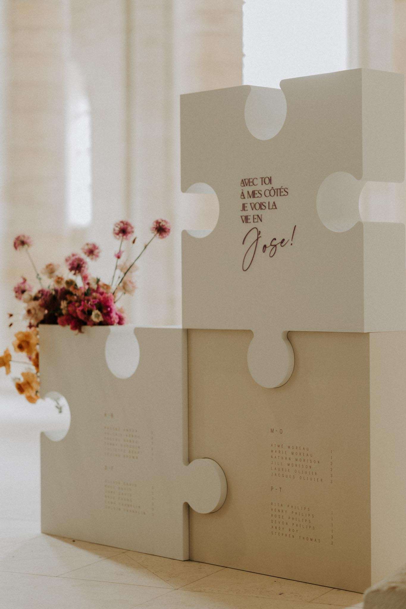 Puzzle-piece seating chart with burgundy script dried florals and French phrase in stone venue