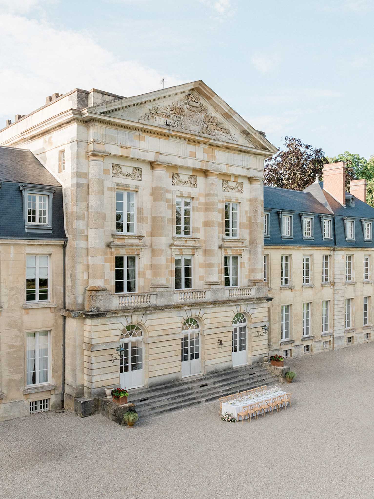 Classical French chateau courtyard with ceremony chairs and floral aisle markers at Courtomer
