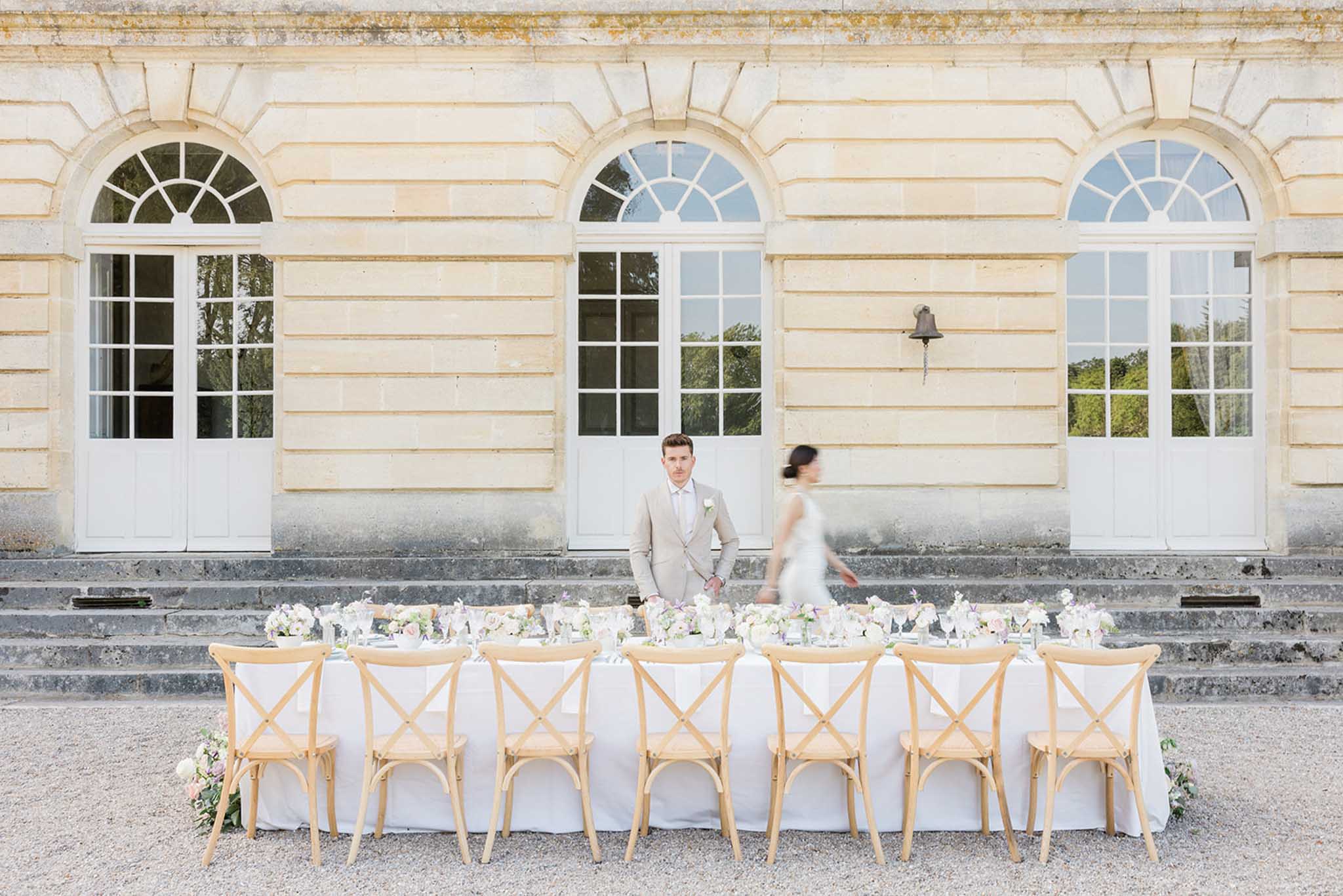 Bride and groom during reception in front of classical stone building with arched windows