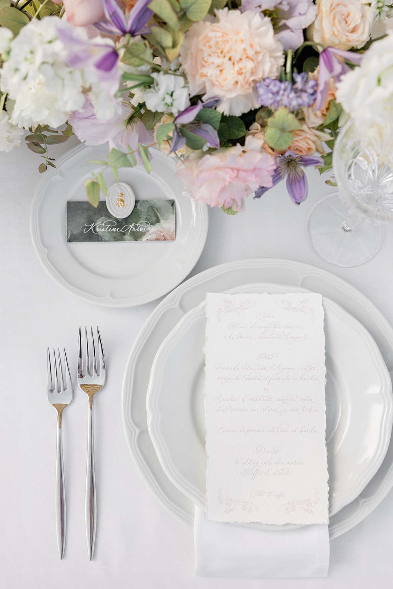 Overhead place setting with scalloped plates, sage place card, and garden roses with lavender sweet peas
