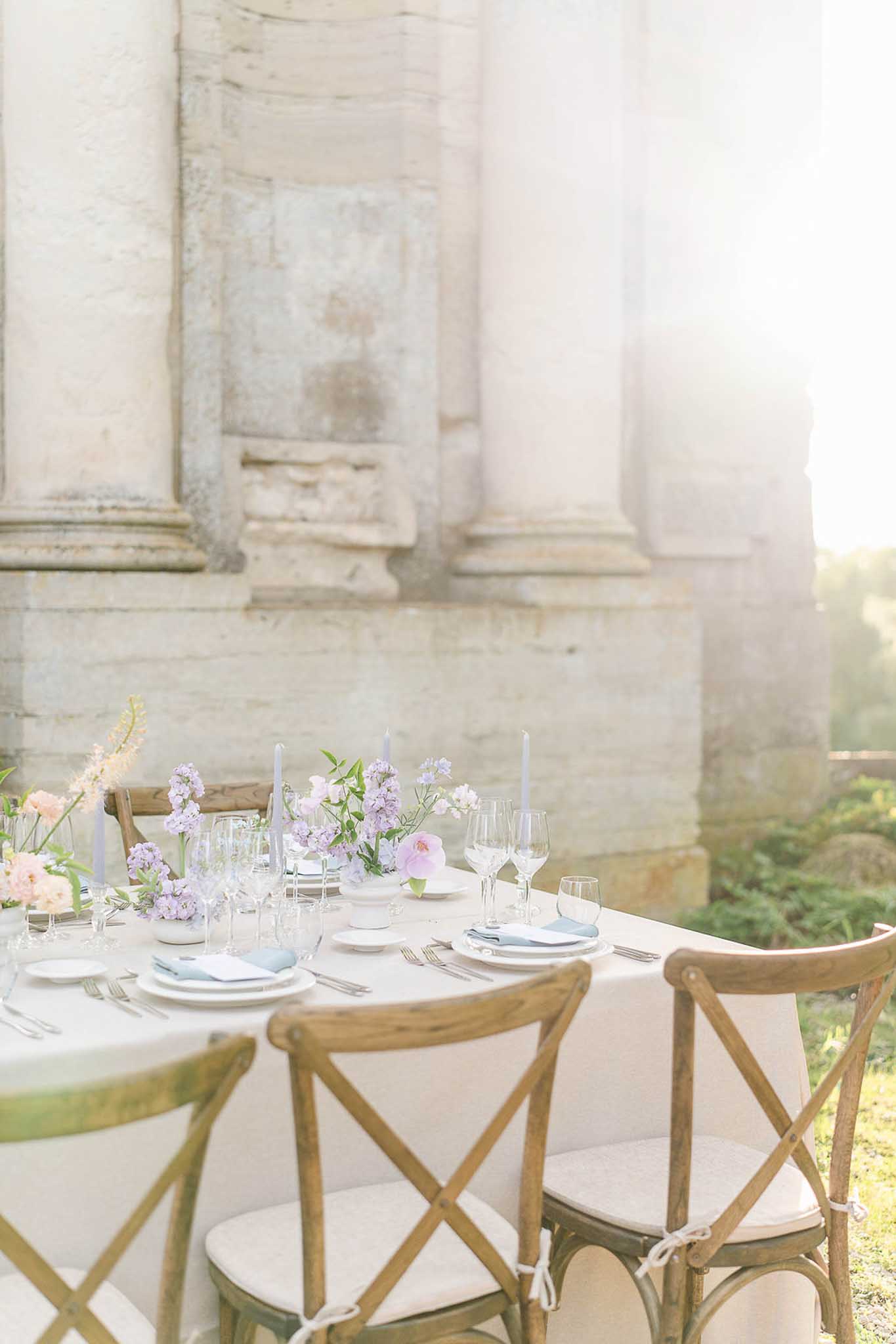 Round reception table with white linens, blue napkins, and taper candles by stone columns