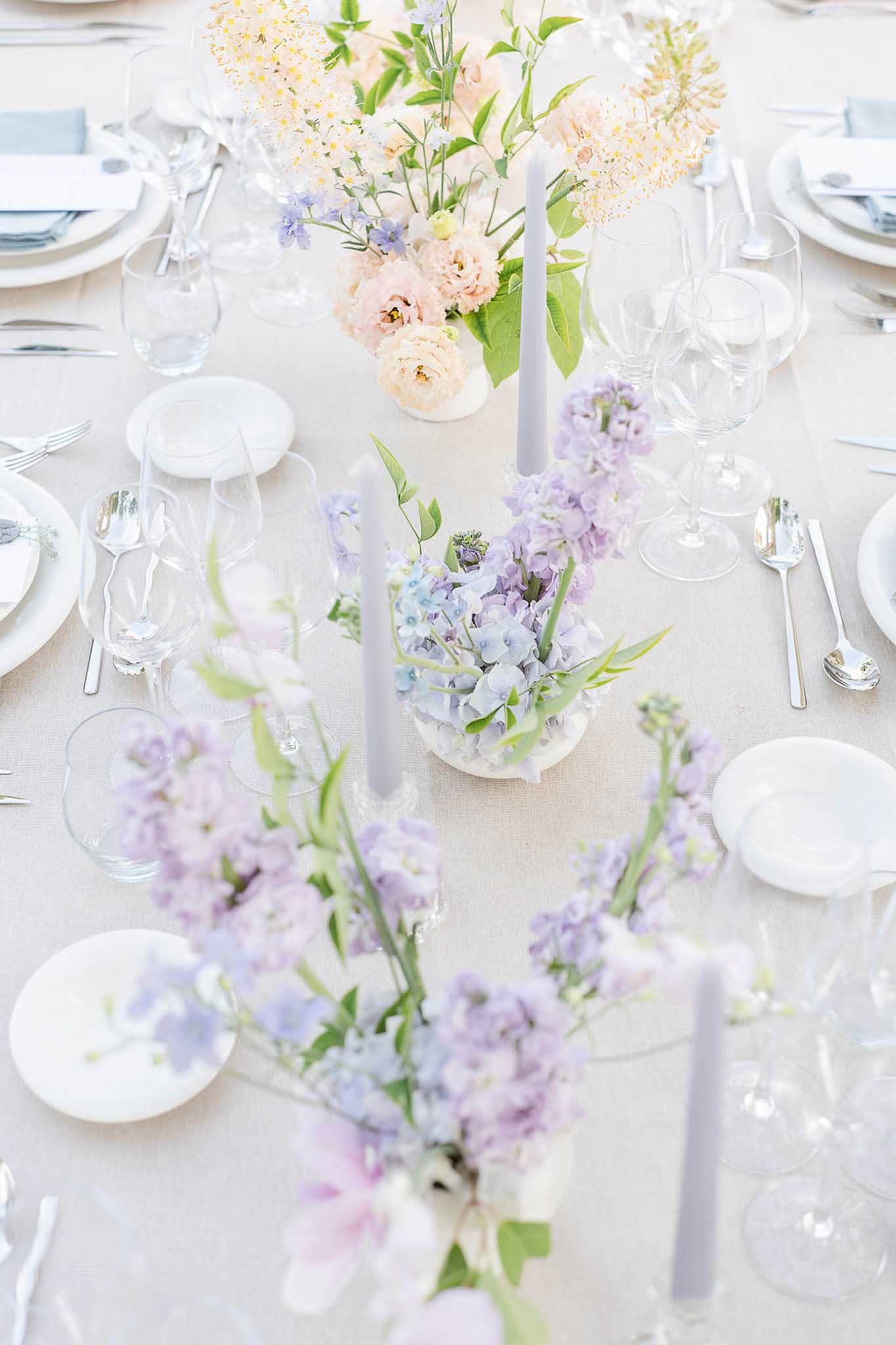 Overhead reception table with peach roses, lavender hydrangeas, white taper candles, and silver flatware