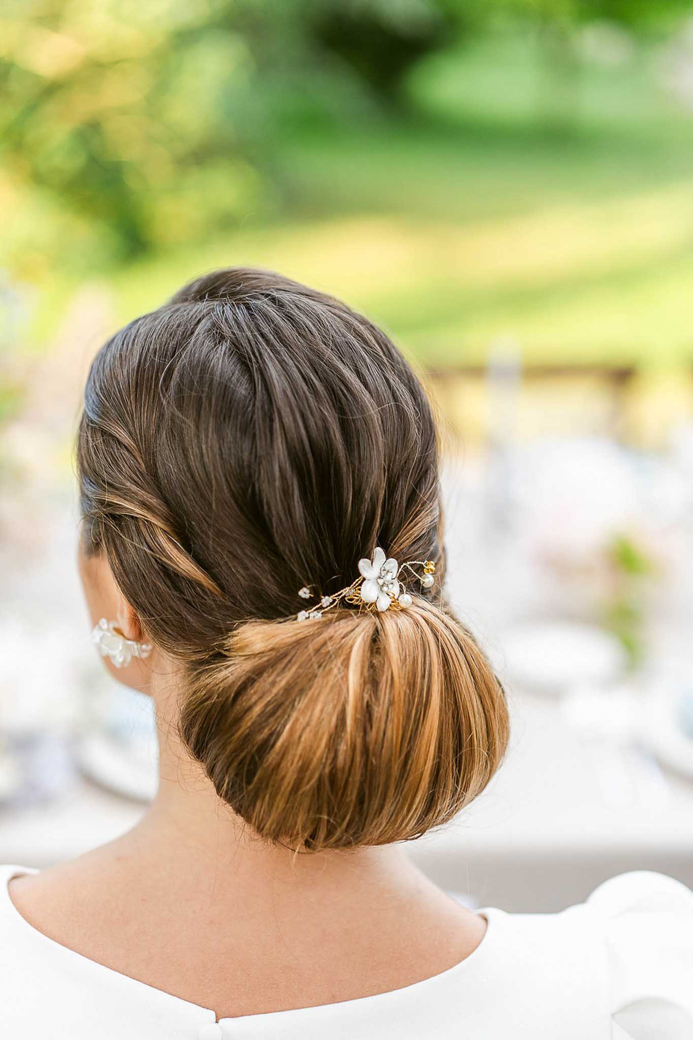 Close-up of bride's low bun hairstyle with gold and pearl floral hair accessory