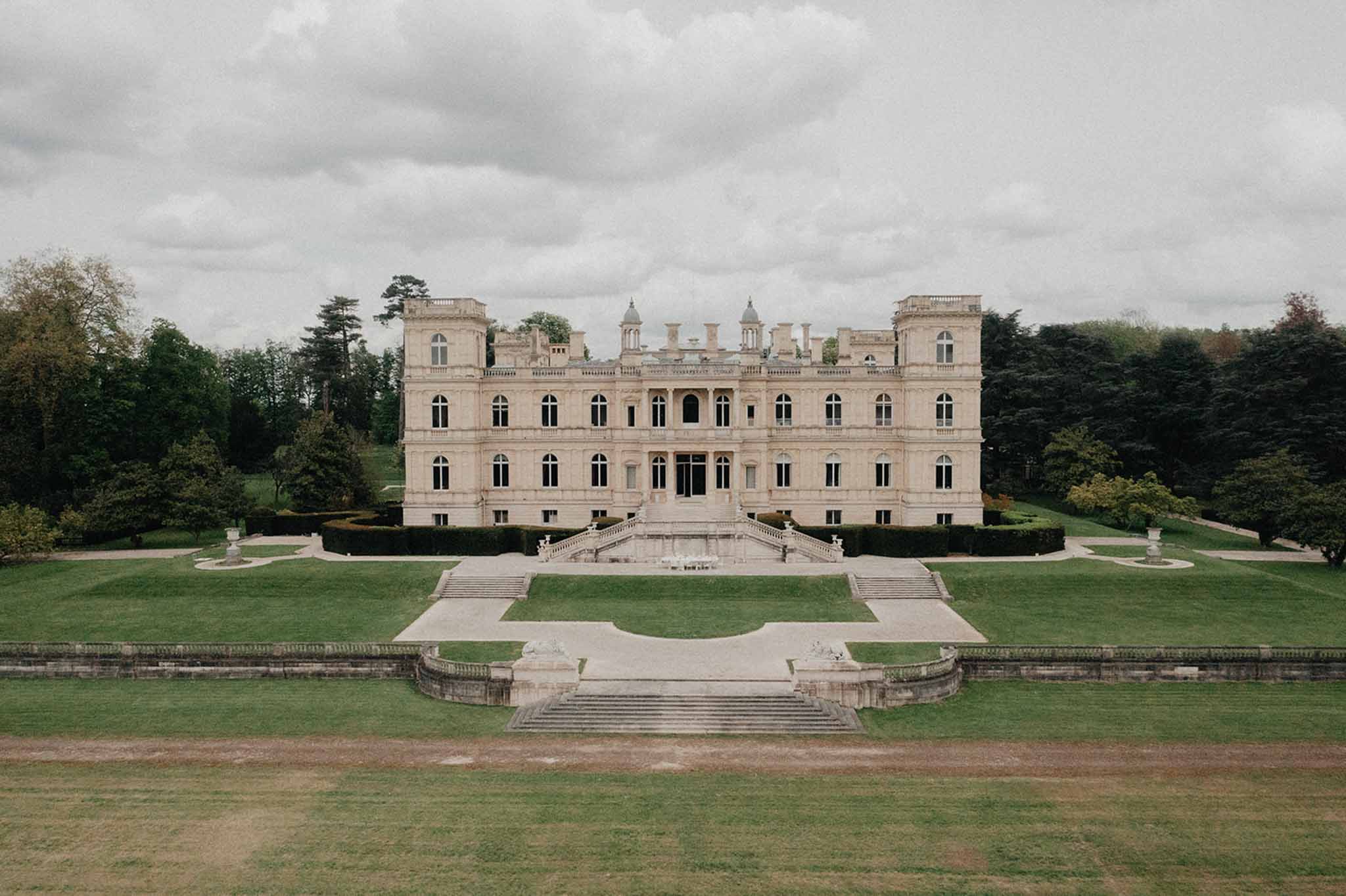 Grand neoclassical chateau with symmetrical facade, towers, and formal stone staircase