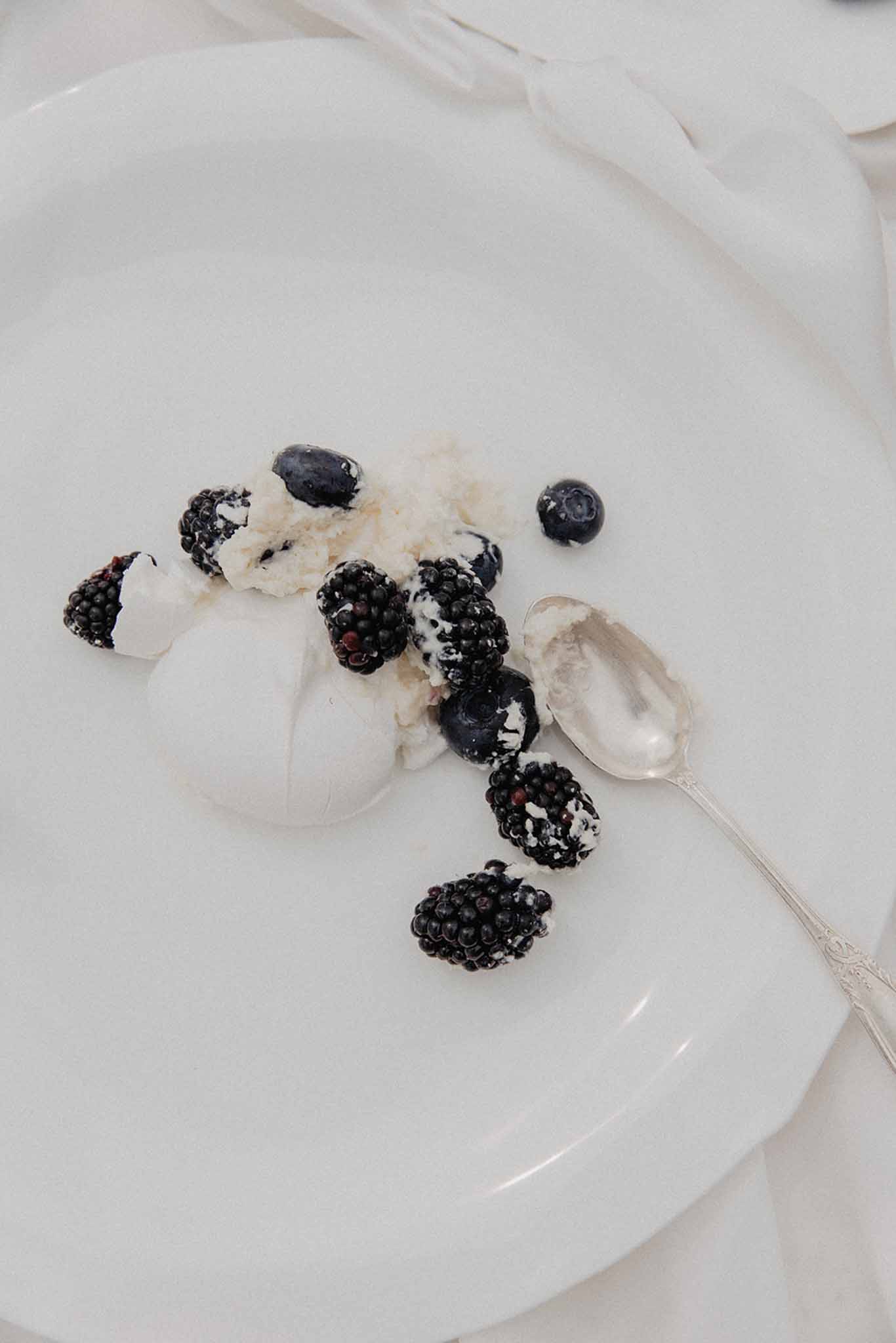 Plated dessert of vanilla mousse with fresh blackberries and blueberries on white plate
