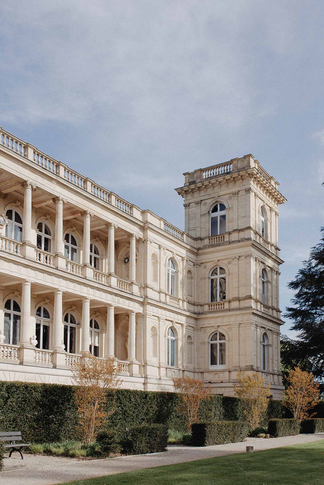 Grand neoclassical chateau exterior with cream stone facades, classical columns, and mansard roof tower