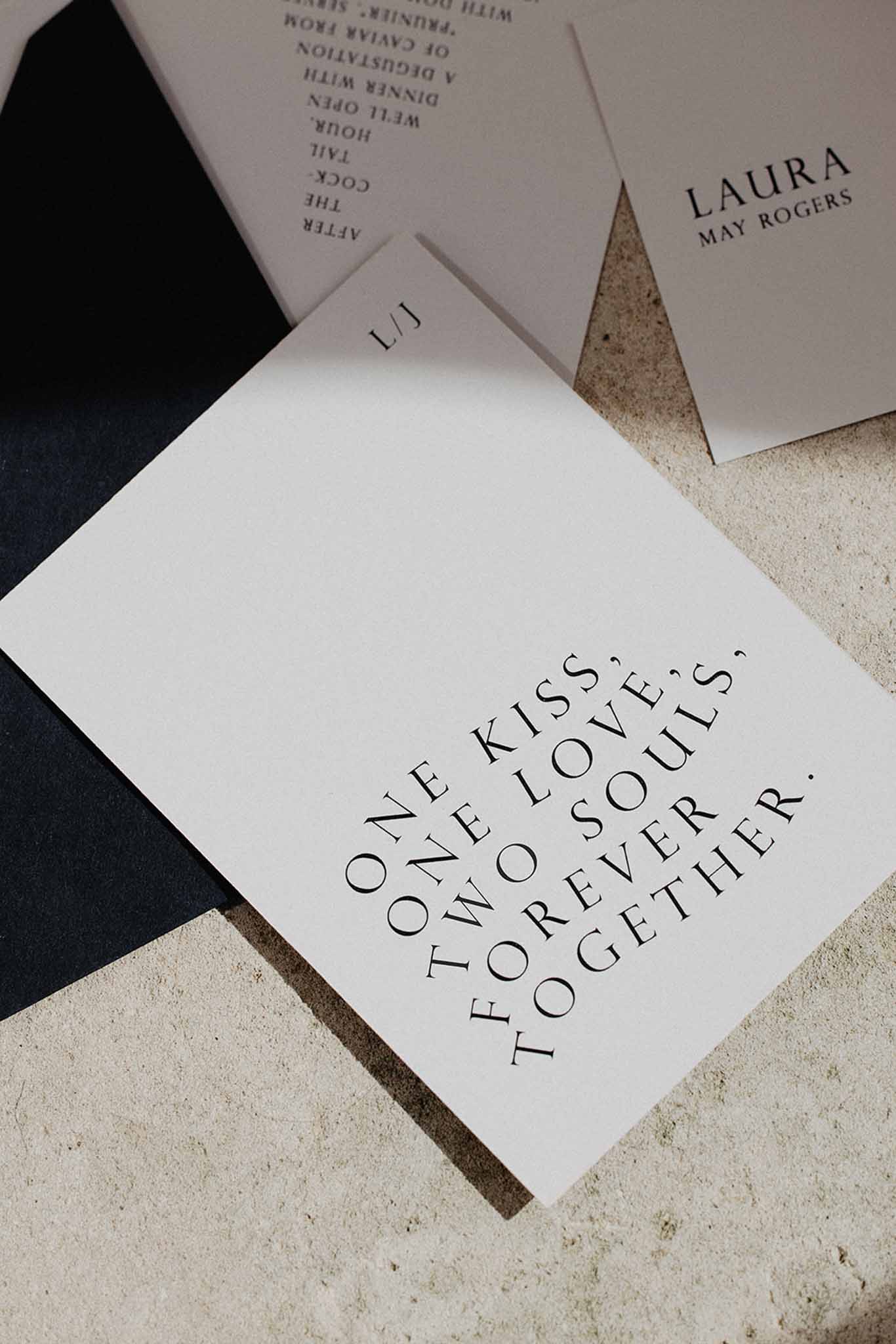 Wedding stationery flat lay with cream and white printed cards featuring serif typography on a textured surface