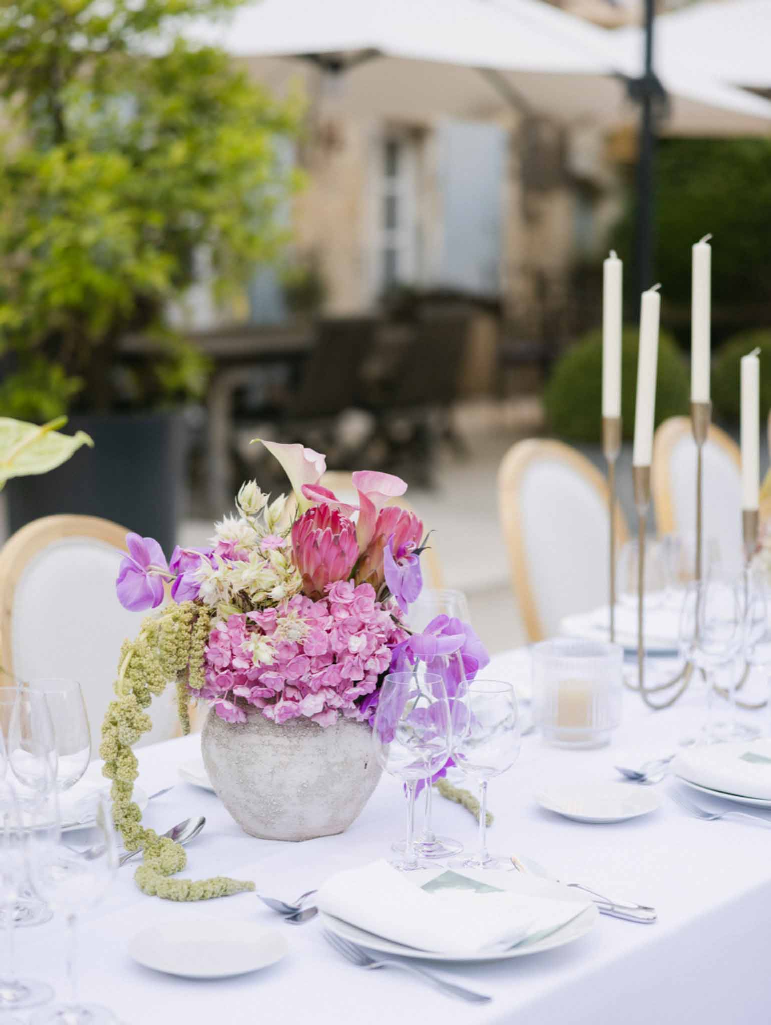 Gray vessel with hot pink hydrangeas, peony, purple sweet peas, and chartreuse amaranthus at outdoor reception table