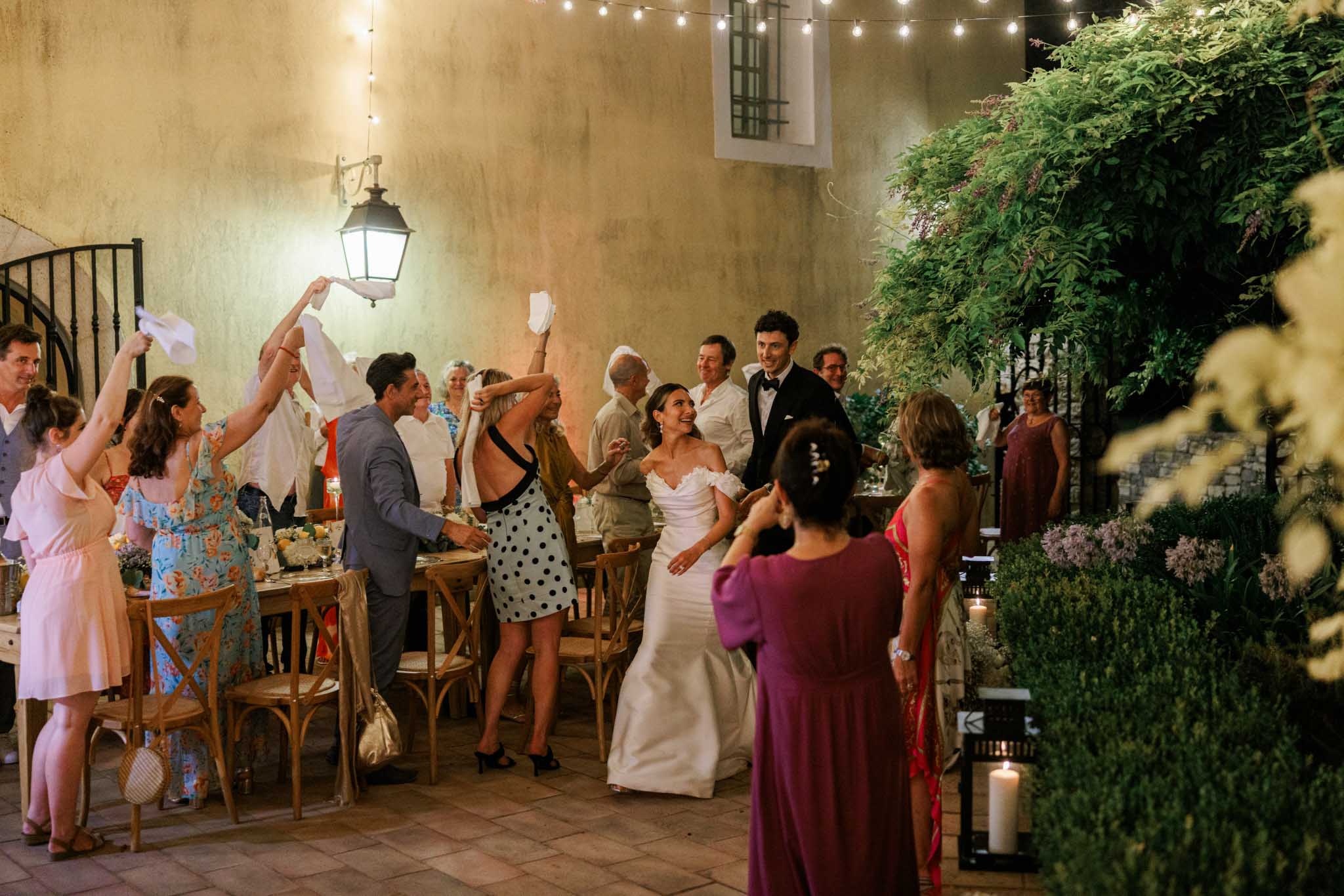 Bride and groom dancing with guests in historic stone courtyard during reception