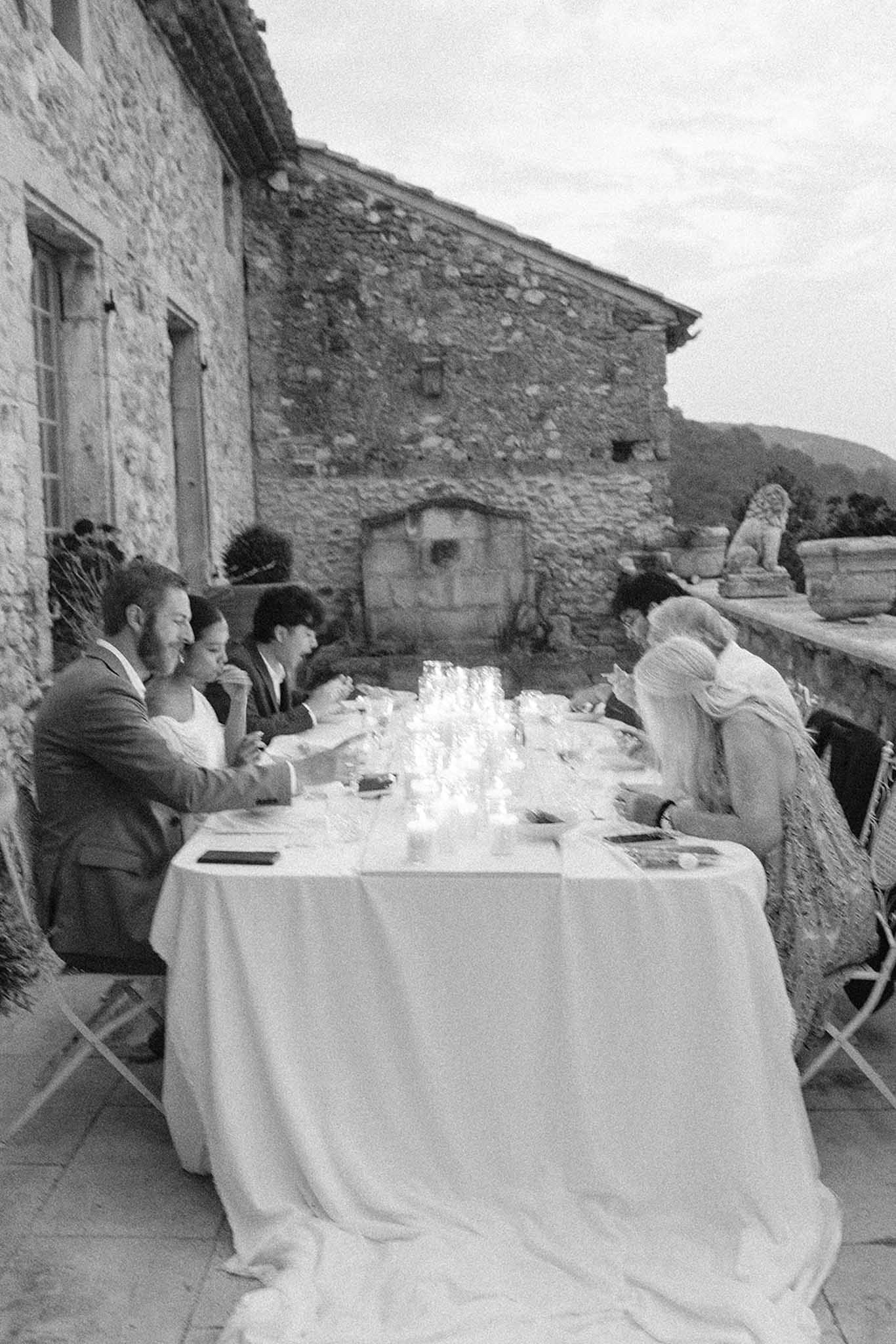 Black and white photo of outdoor reception meal at a rustic stone building in the countryside
