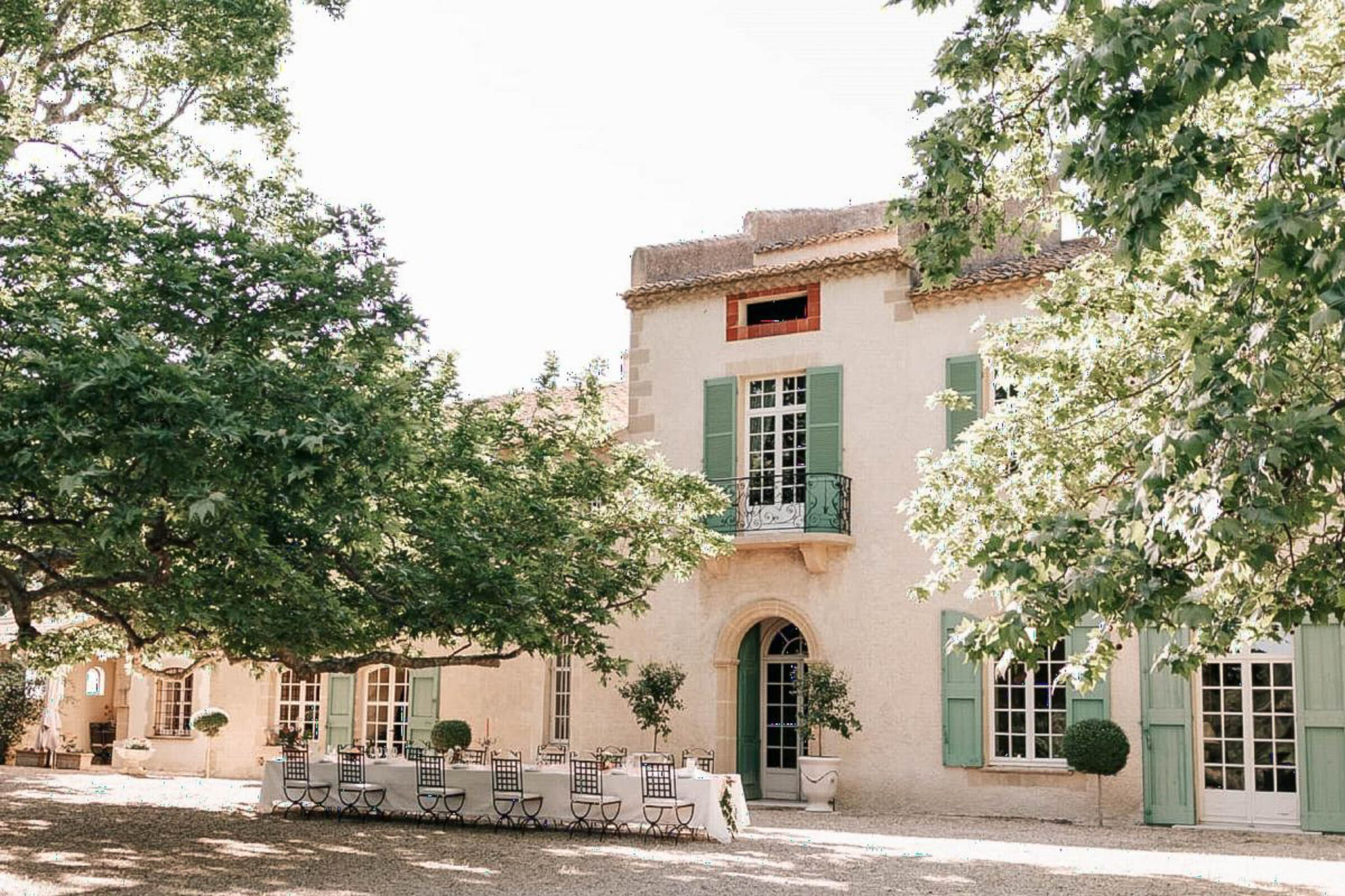 Provencal mas with sage shutters, arched doorways, and long white reception table with boxwood topiaries