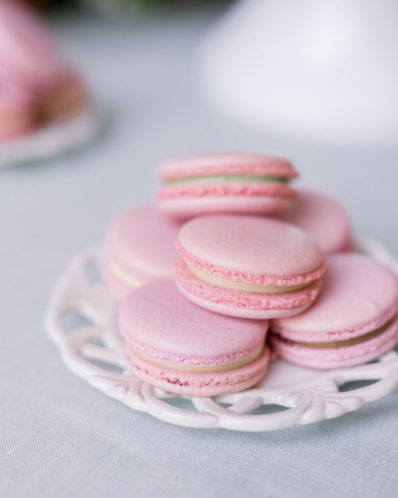 French macarons in pale pink on ornate white porcelain plates at wedding dessert display