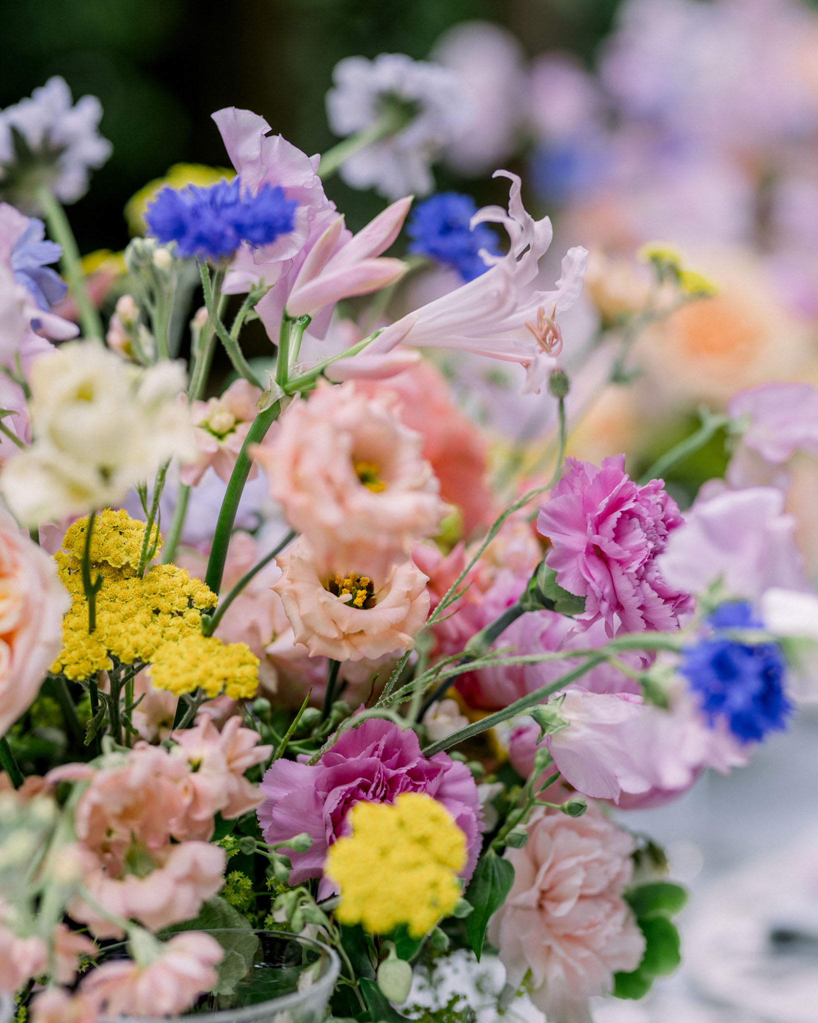 Vibrant mixed flower arrangement with pink peonies, yellow scabiosa, and green foliage