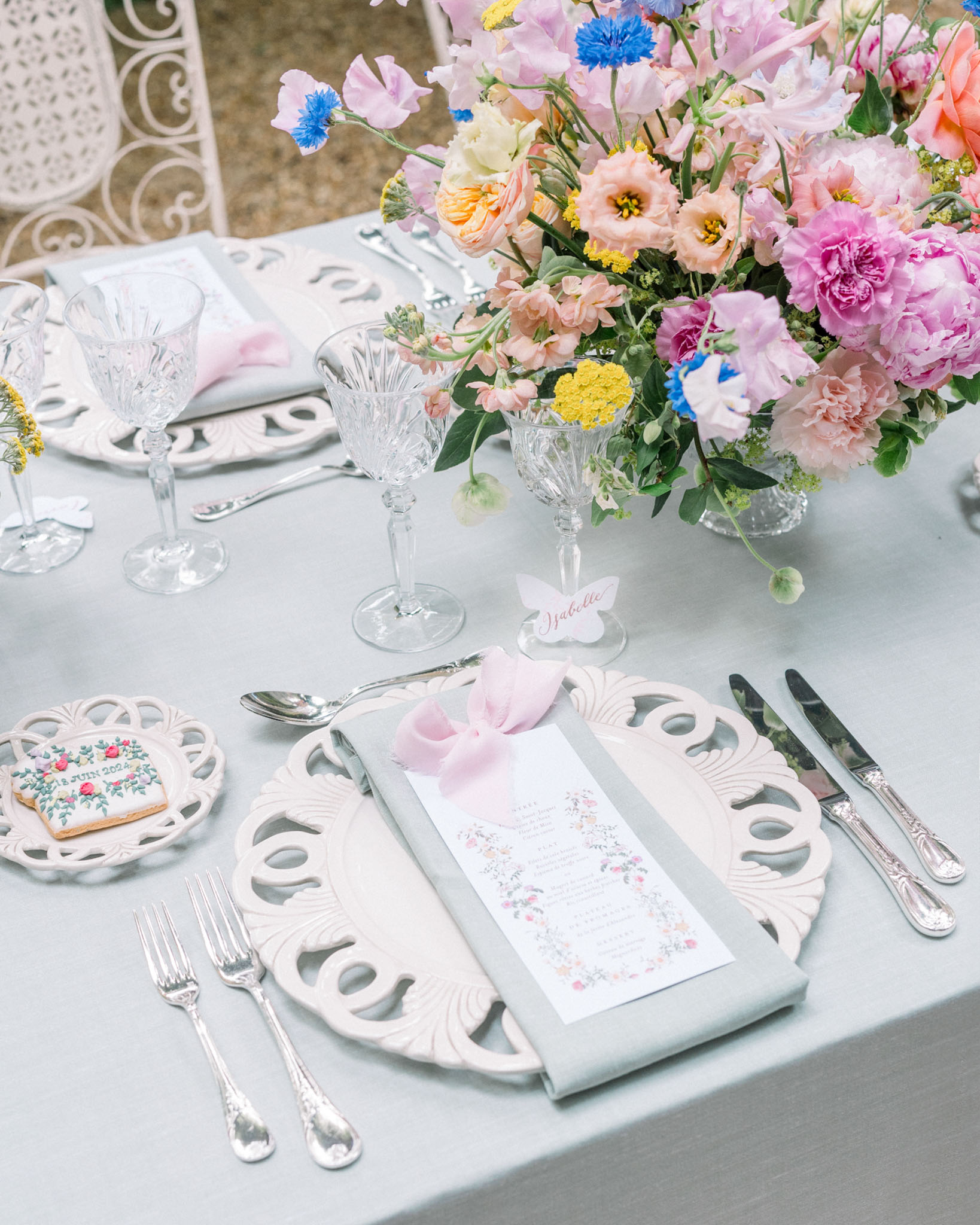 Reception place setting with pink peonies, blue cornflowers, and ornate silver-rimmed plates