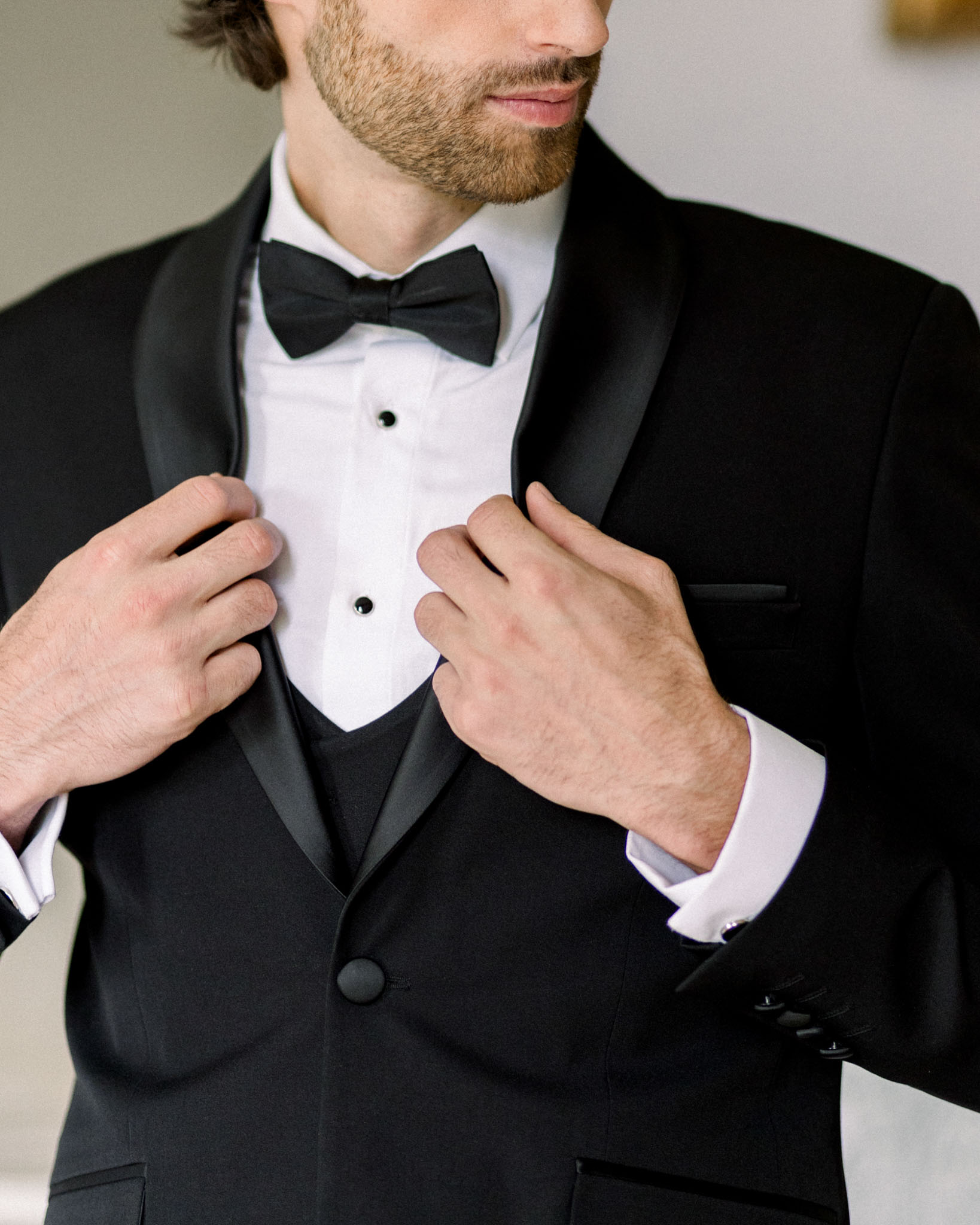 Groom adjusting his tuxedo and cufflinks during wedding preparations