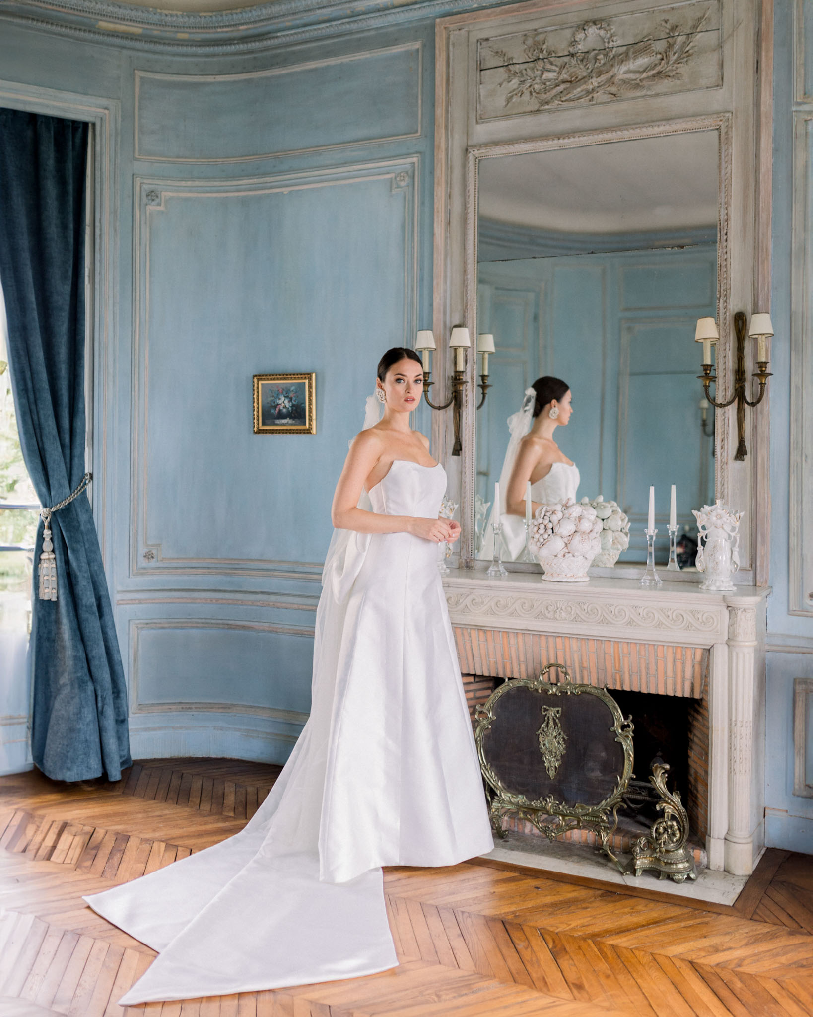Bride in strapless gown posing in neoclassical salon with blue-grey panelled walls