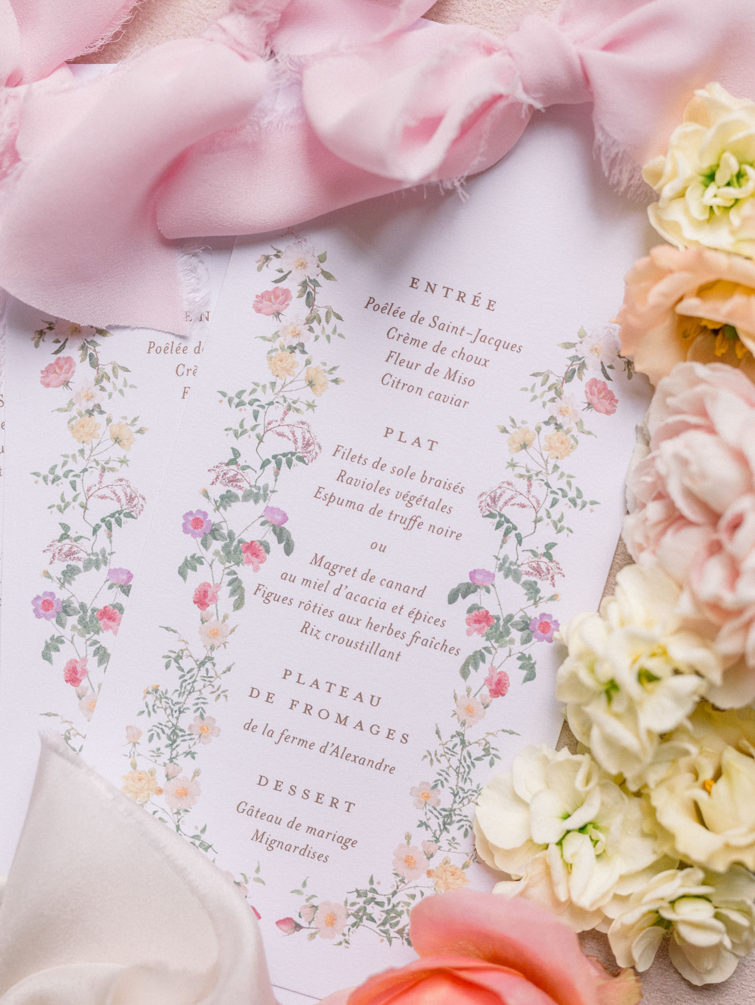 French wedding menu card with botanical border surrounded by pink tulle and cream garden roses