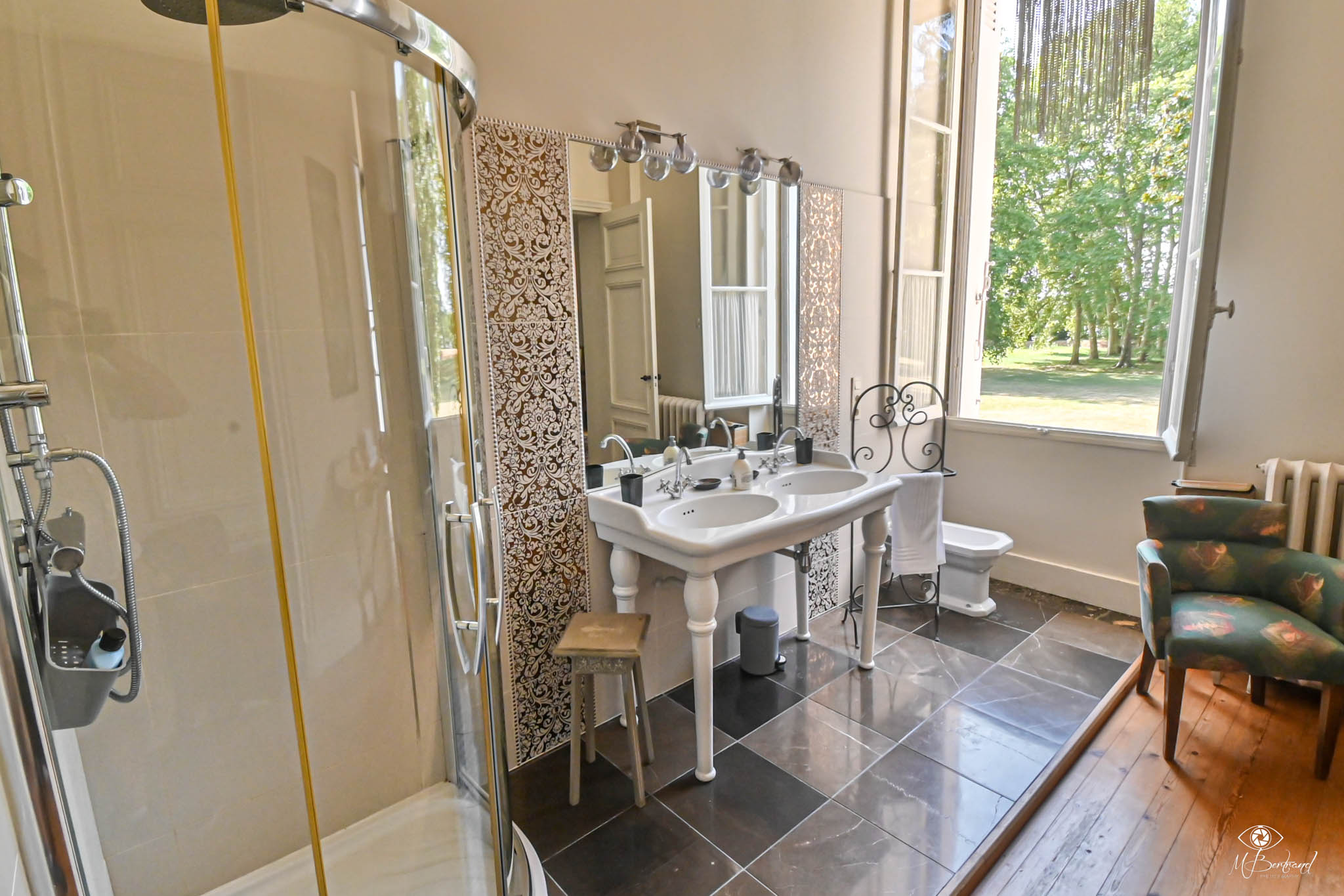 Chateau bathroom with pedestal sinks damask tiles glass shower and garden-view window