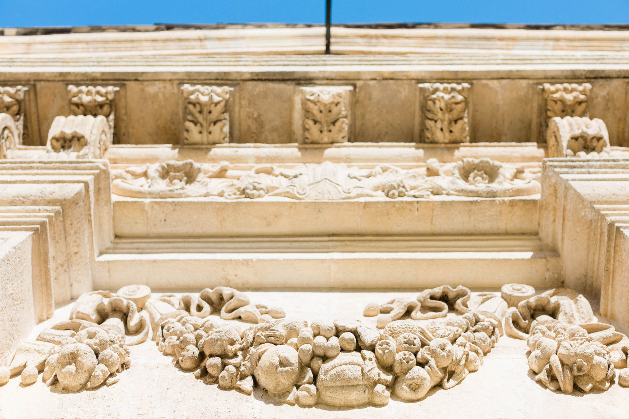 Carved limestone facade detail showing fruit garland relief sculptures and acanthus leaf corbels