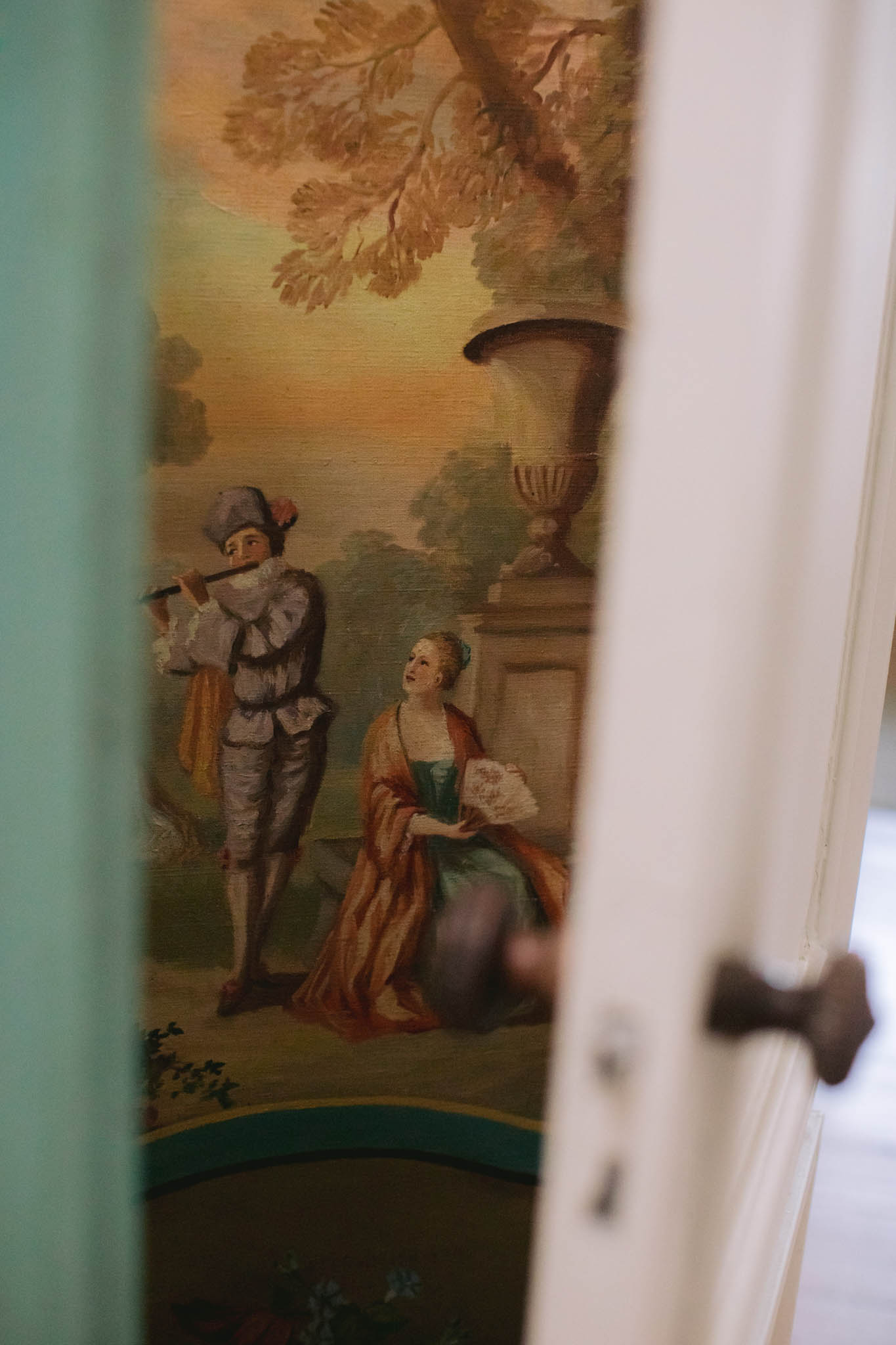 Eighteenth-century pastoral mural glimpsed through partially open white door in chateau interior