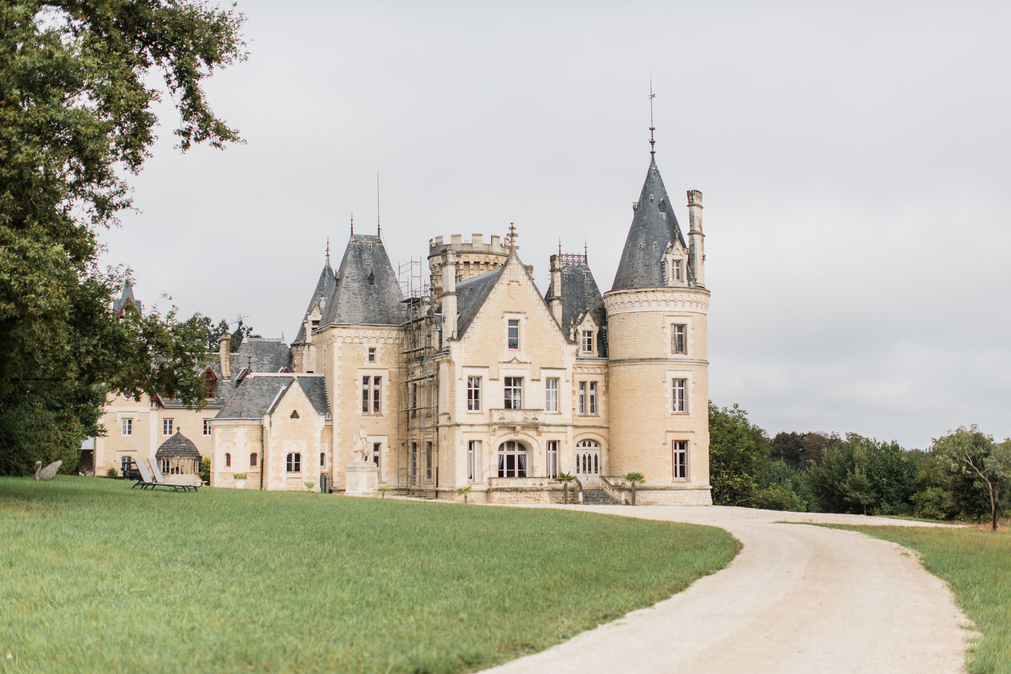 Cream stone chateau with conical towers and slate roofs set in manicured grounds