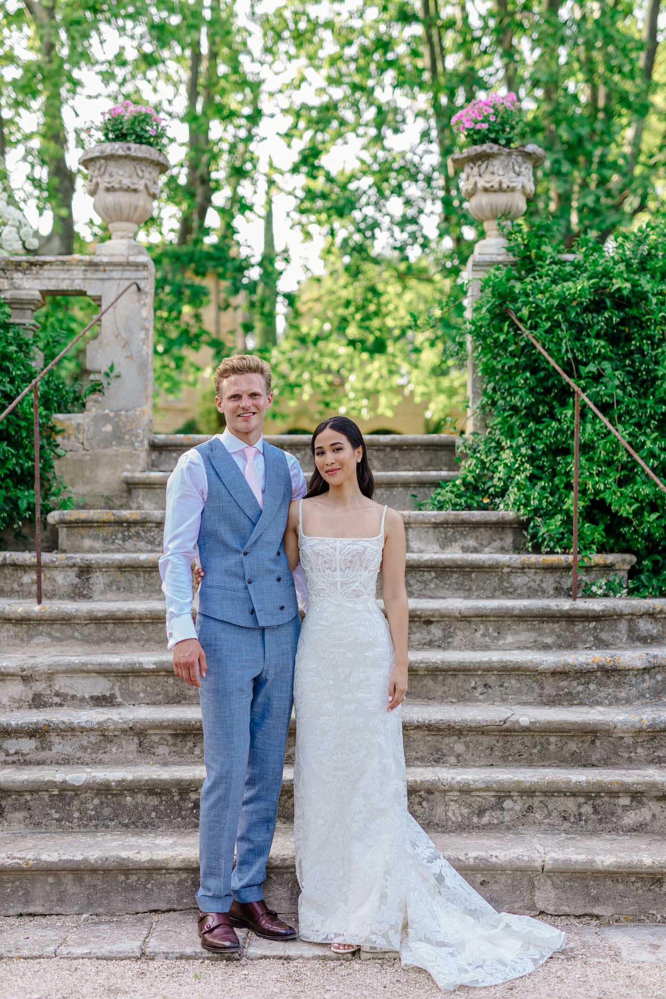 Bride and groom on stone garden staircase lined with cypress trees and ivy walls