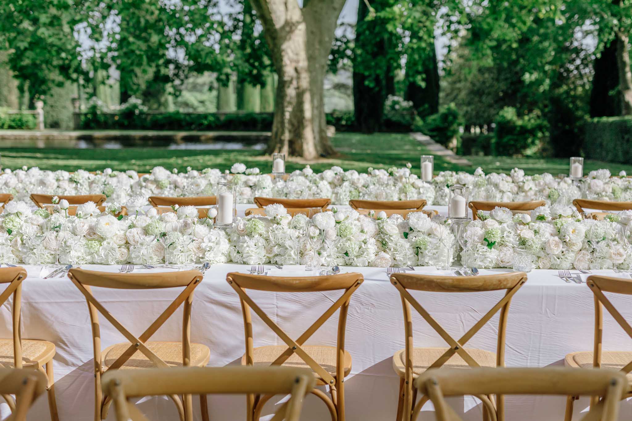 Long reception table with white hydrangea and rose centrepiece and cross-back chairs