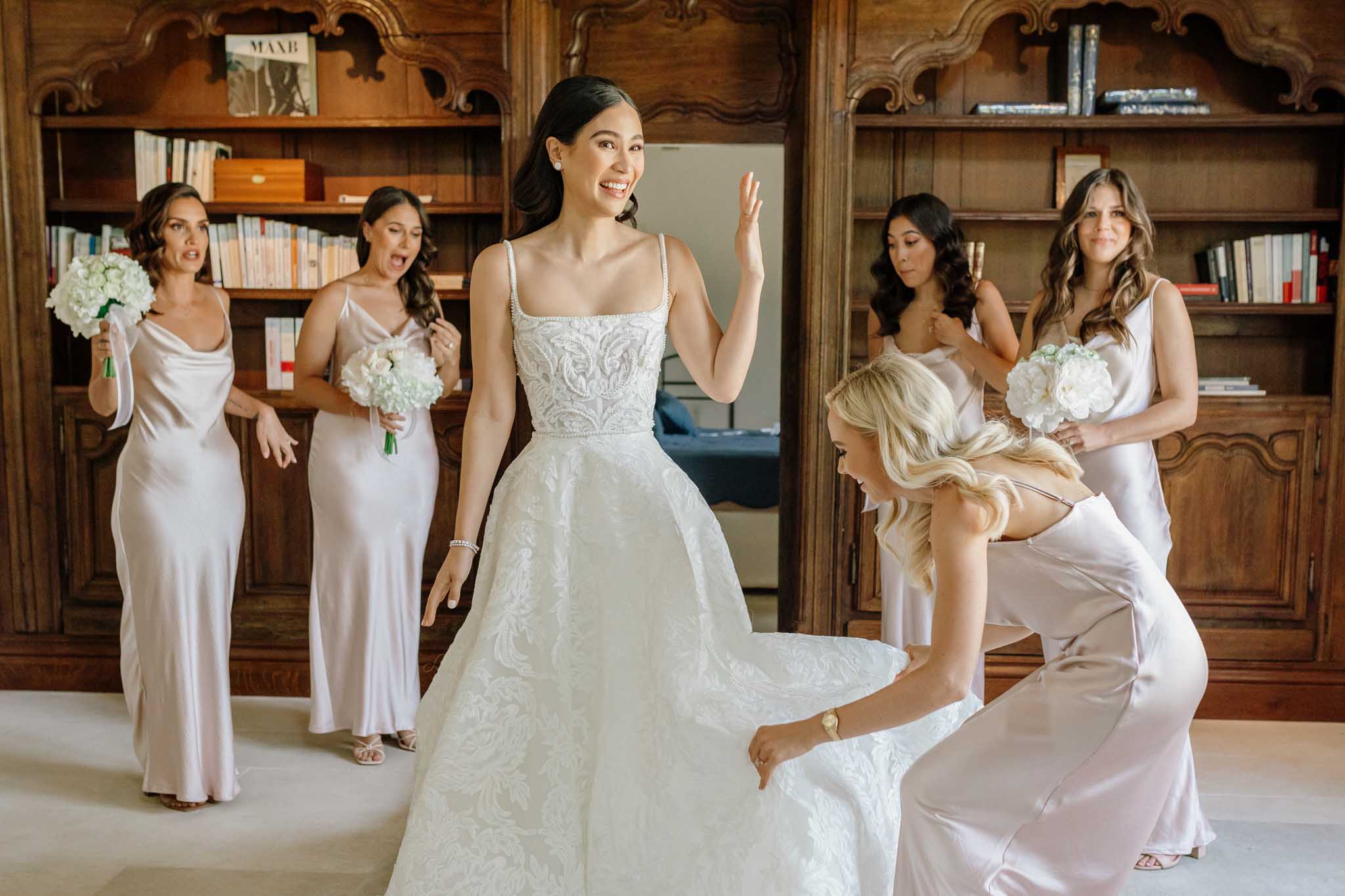Bride in embellished ivory ball gown with five bridesmaids in champagne dresses in classical library setting