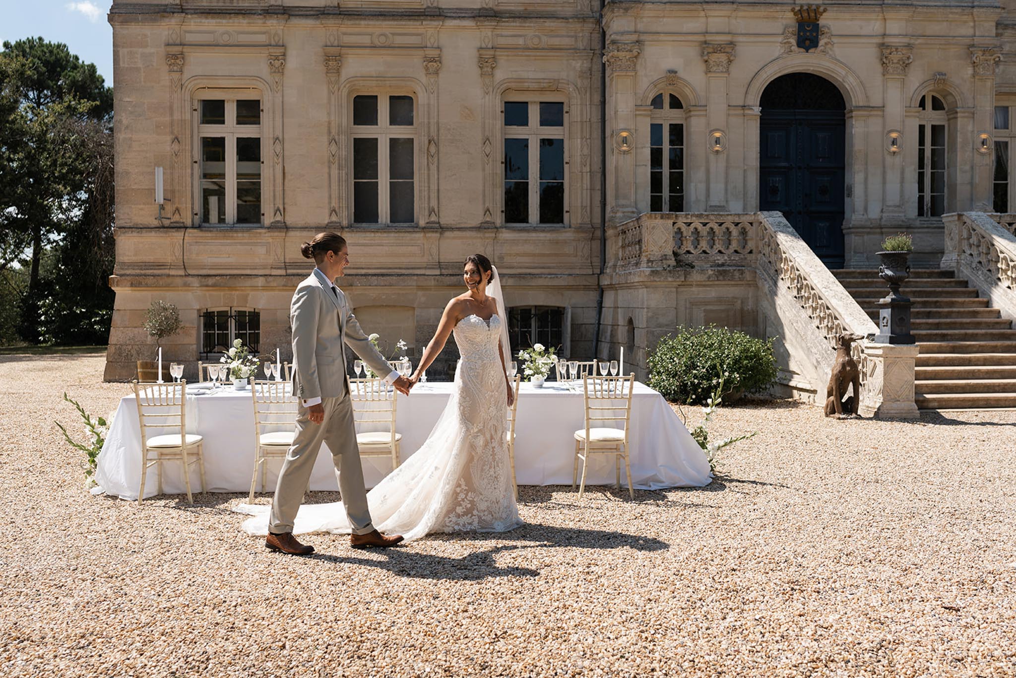 Bride and groom walking through outdoor reception with white rose centerpieces at classical manor