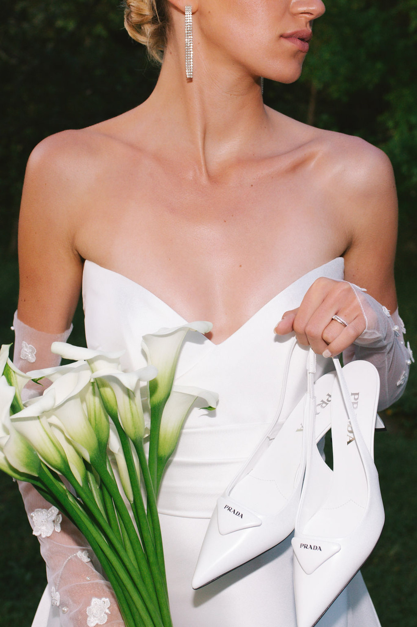 Bride in ivory gown walking through garden at Domaine de Lamanon with floral arrangement