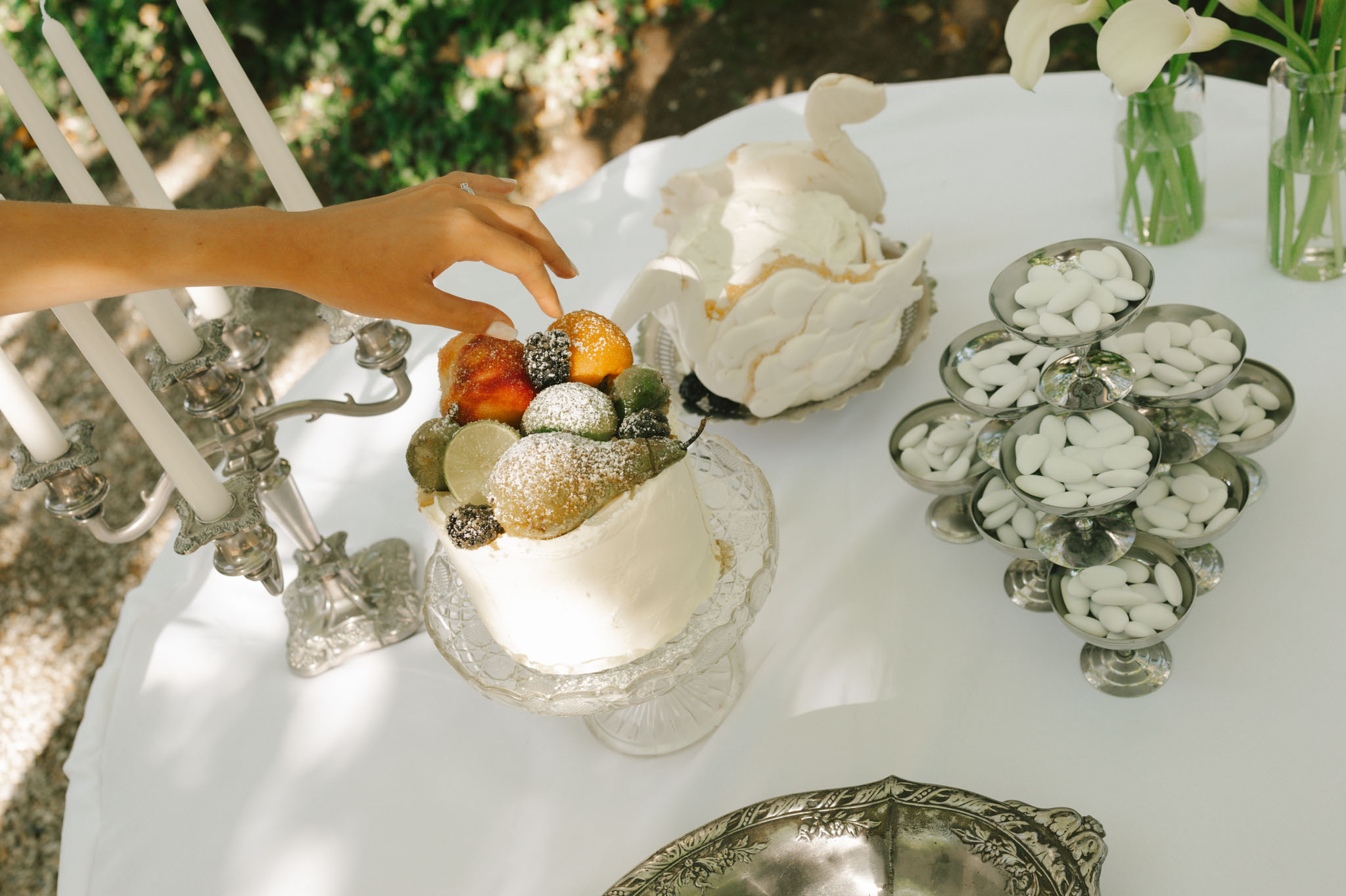 Dessert table with individual cream cakes on crystal stand, Jordan almonds in crystal bowls and white calla lily arrangements