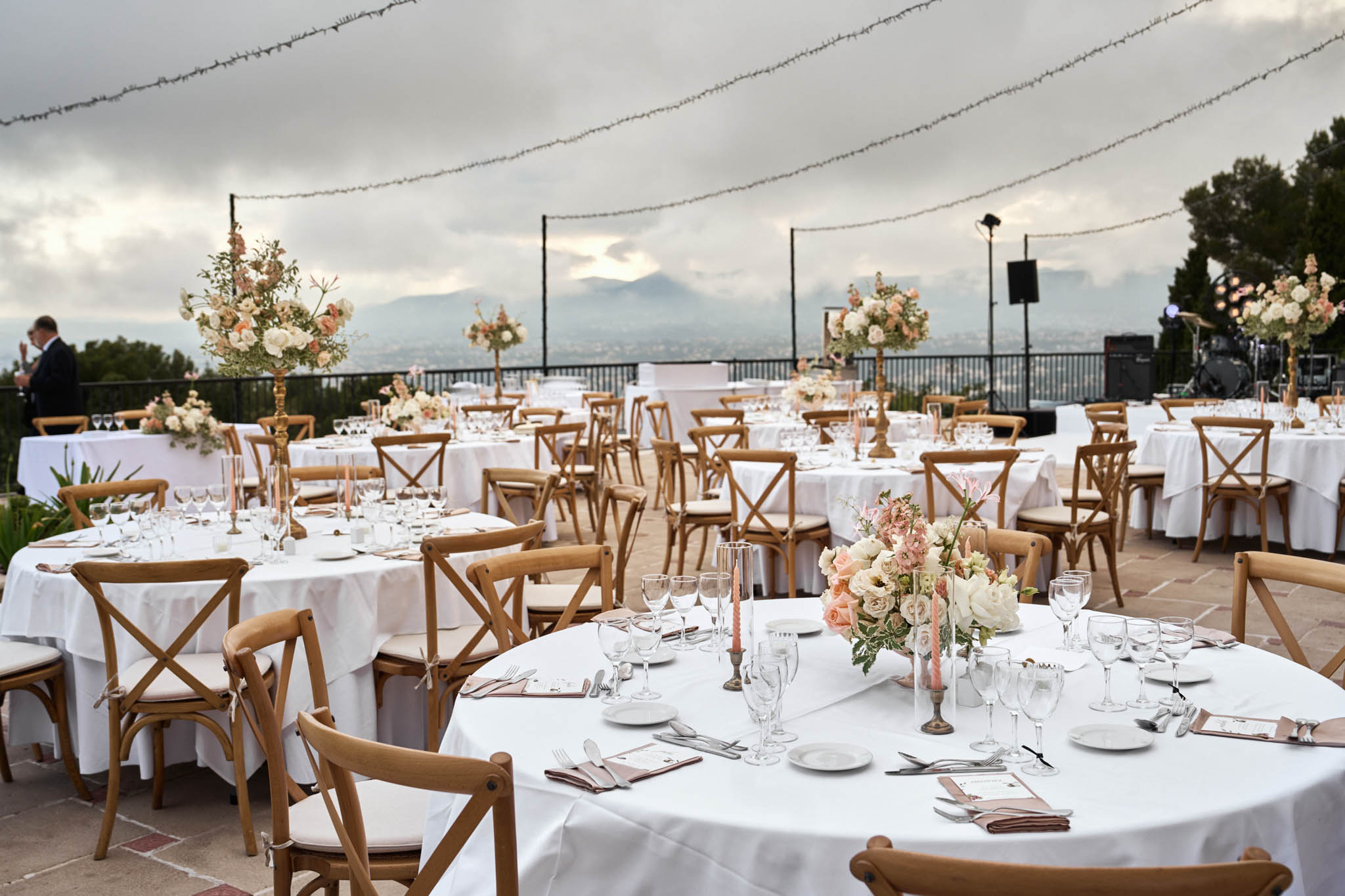 Terrace reception with mountain view, round tables, peach and blush centerpieces, and gold candelabra stands