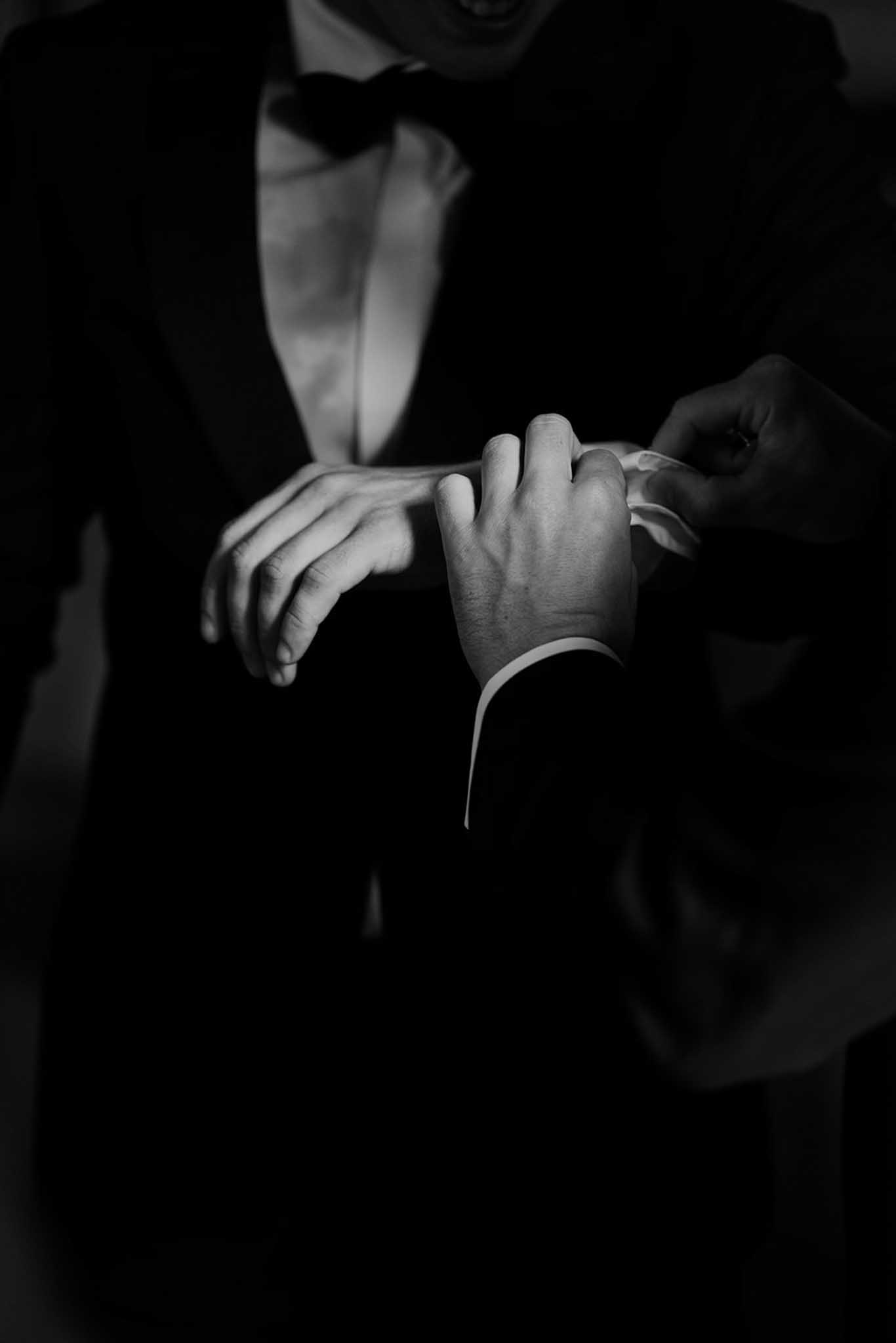 Black and white close-up of bride placing wedding band on groom's finger during ring exchange ceremony