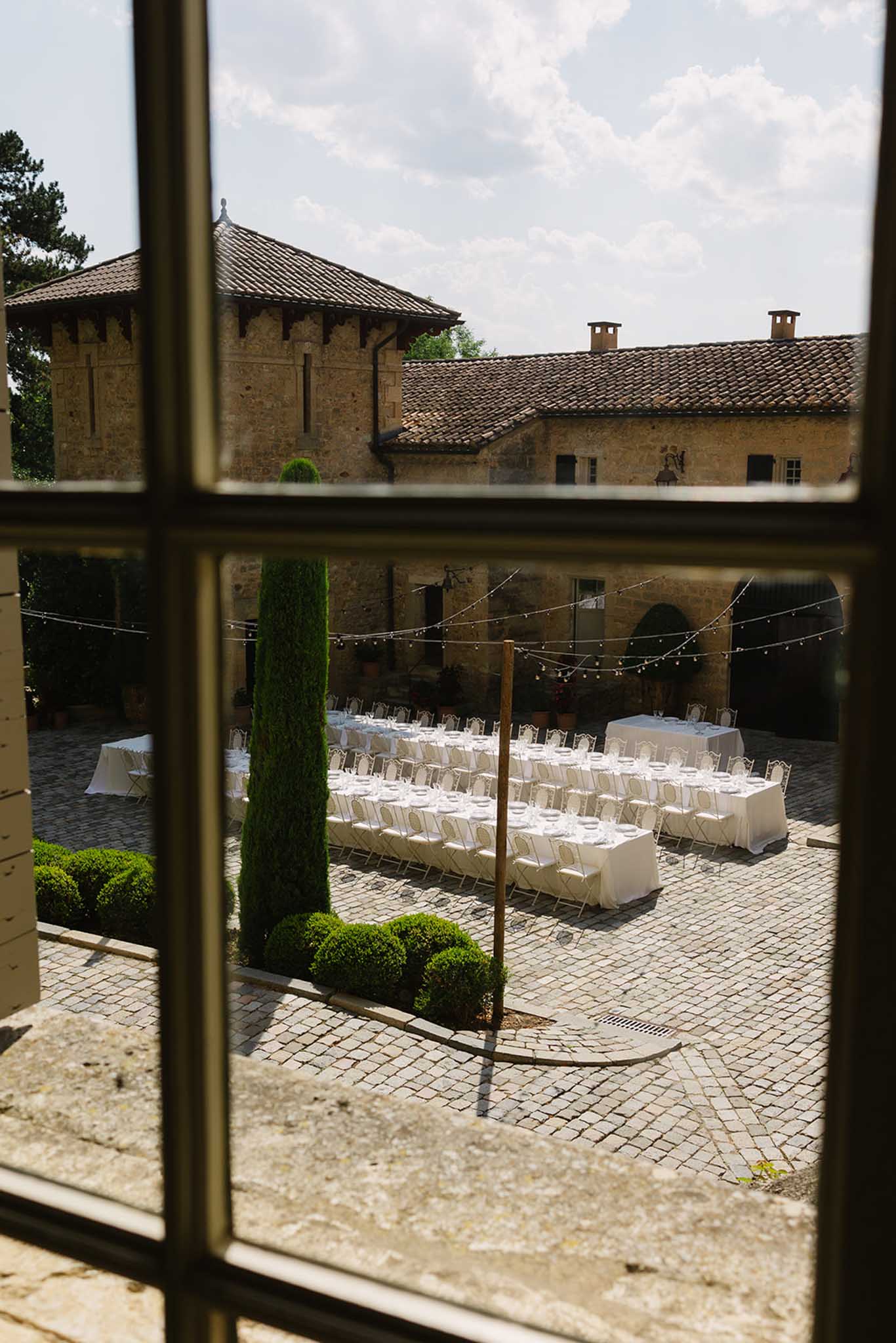 Reception setup at Château de Fontareches viewed through glass window showing tables and floral decor