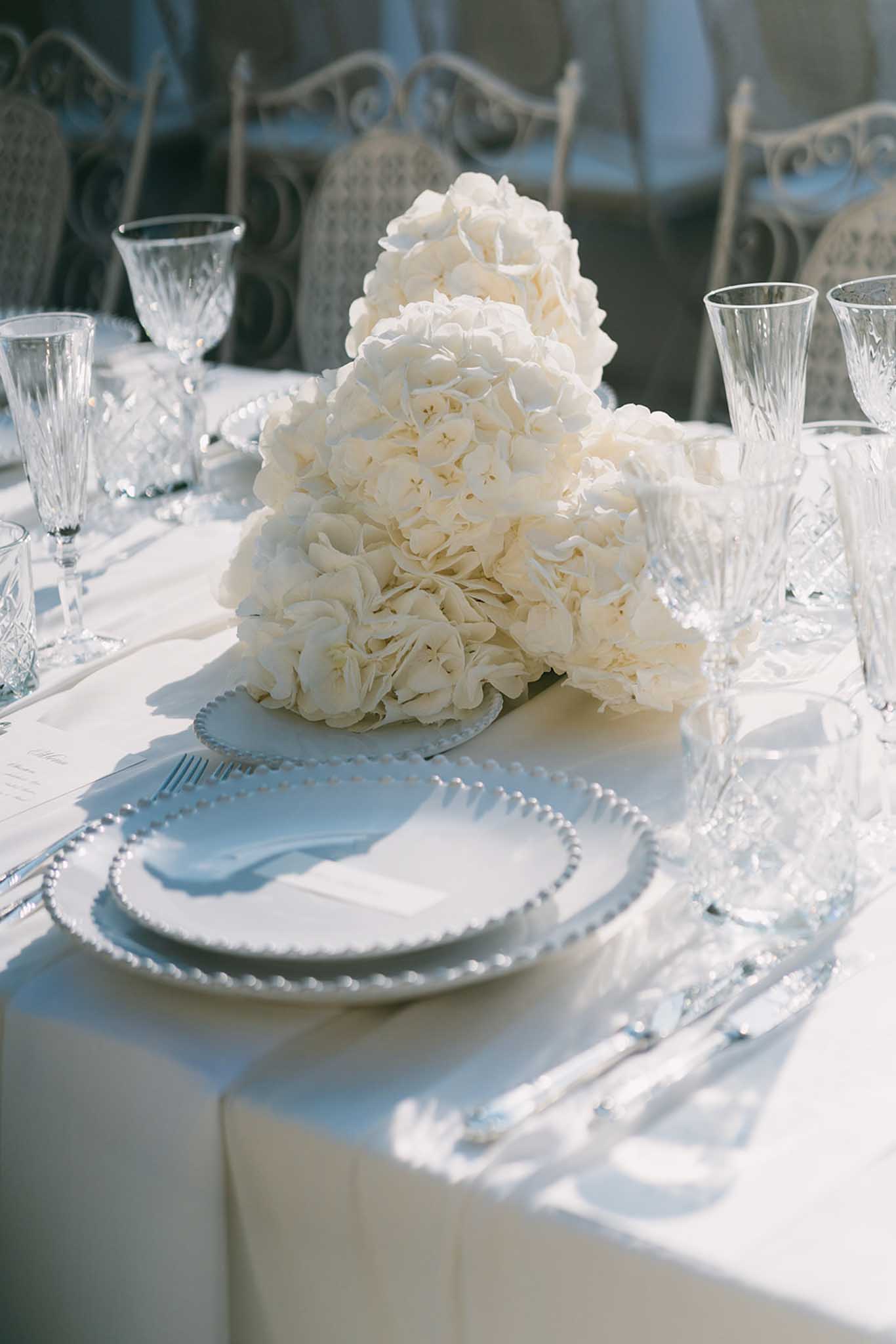 Formal reception table with ivory peony centerpiece on pale blue charger plates and crystal glassware