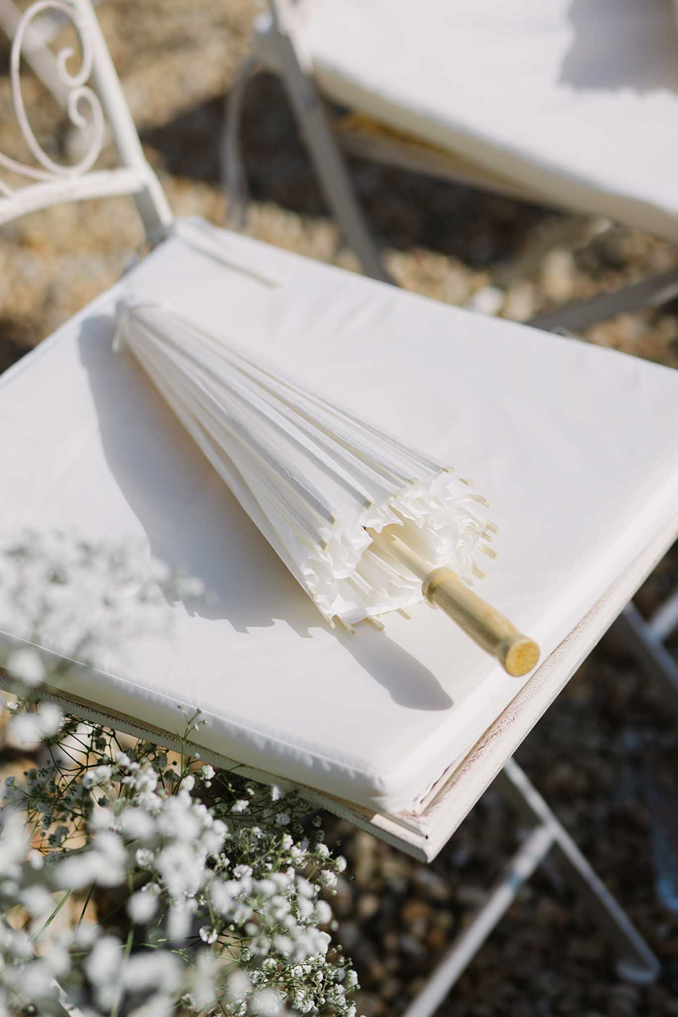 Outdoor ceremony setup at Château de Fontareches with white umbrellas and white chairs in garden