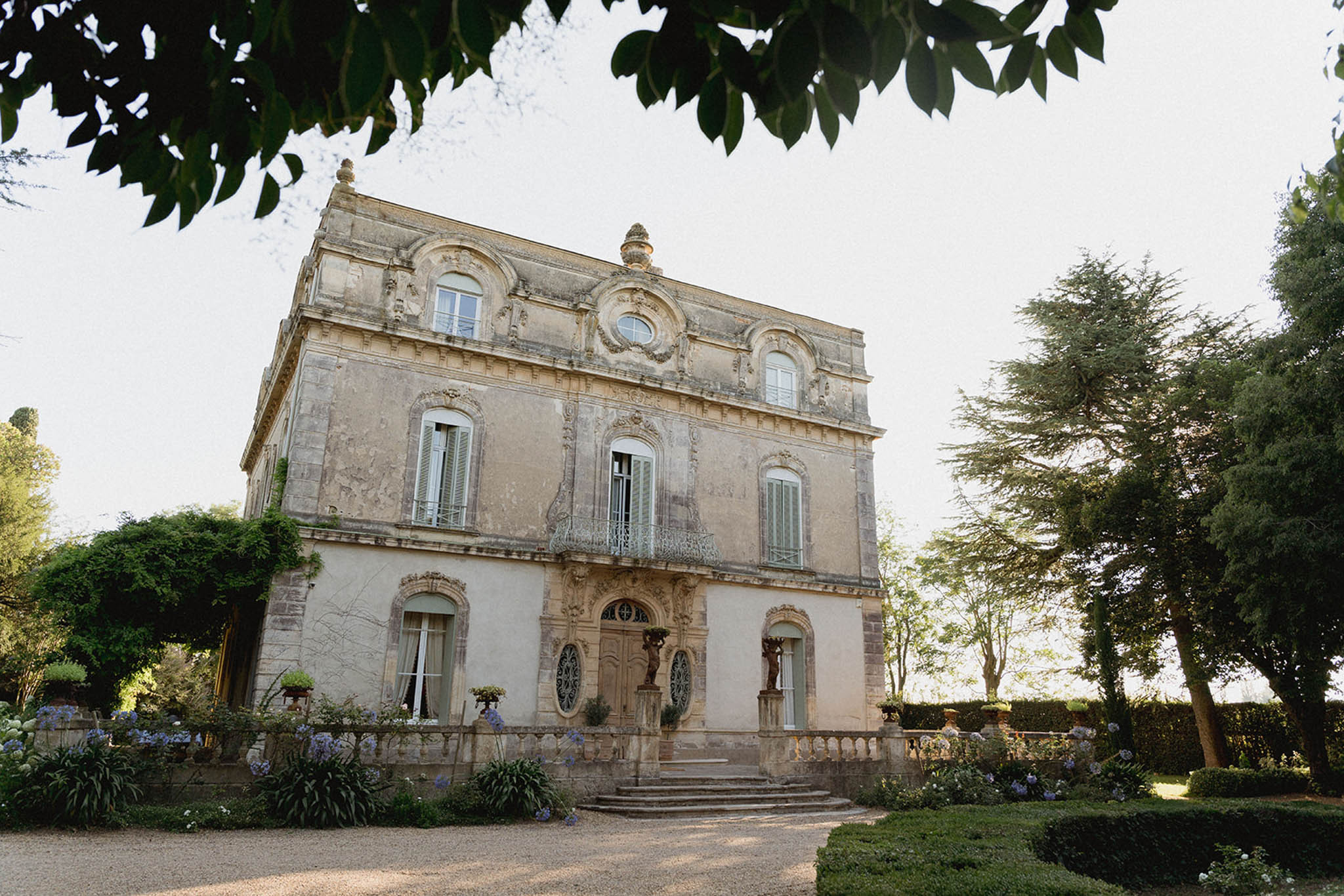 Classical stone mansion with ornate facade set within manicured grounds and cypress trees