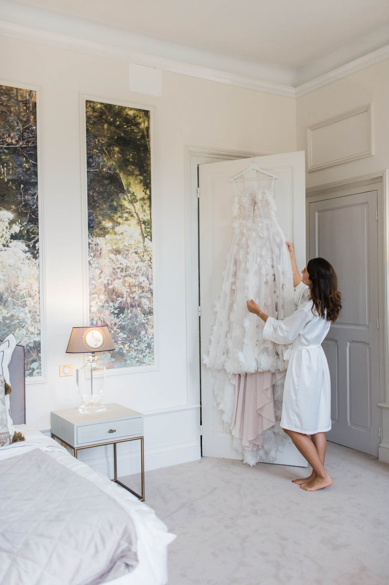 Bride in a white robe adjusting her wedding dress during preparations