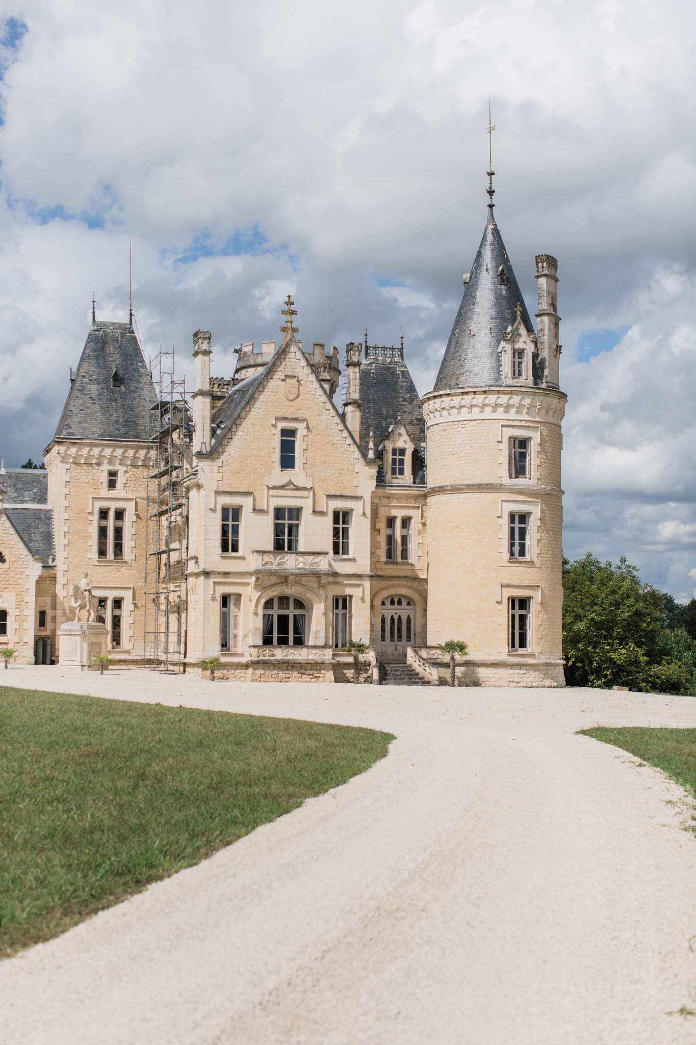 French chateau with cream limestone, slate-roofed conical towers, and Gothic-Renaissance detailing