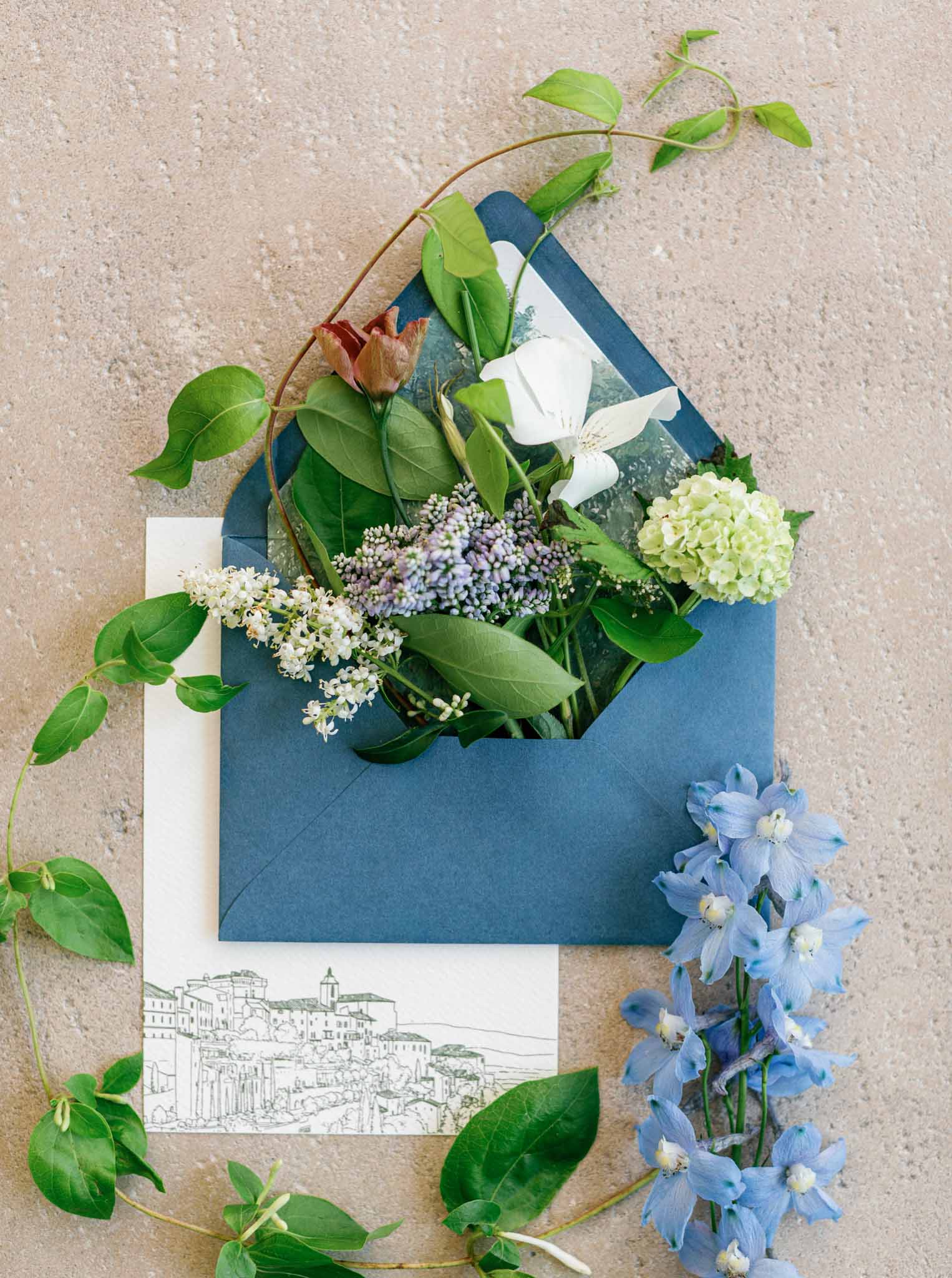 Blue envelope with wild flowers and greenery as stationery detail at Bastide de Gordes wedding
