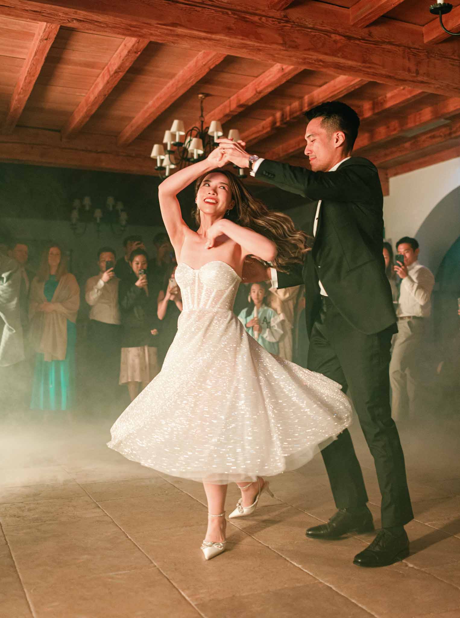 Bride and groom sharing first dance under wooden beam ceiling with chandelier at Bastide de Gordes