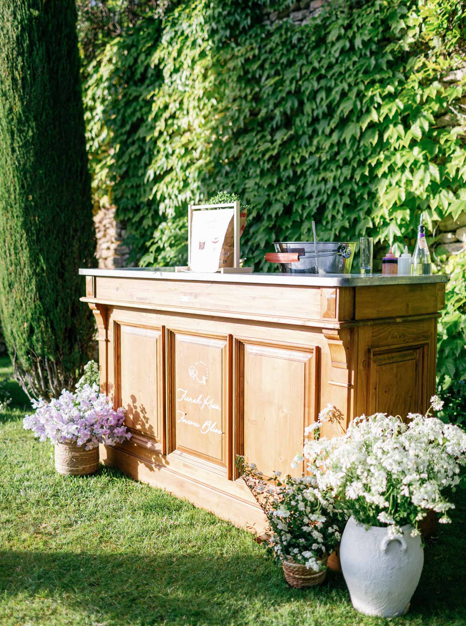 Wooden bar station with marble countertop on lawn during outdoor garden cocktail hour