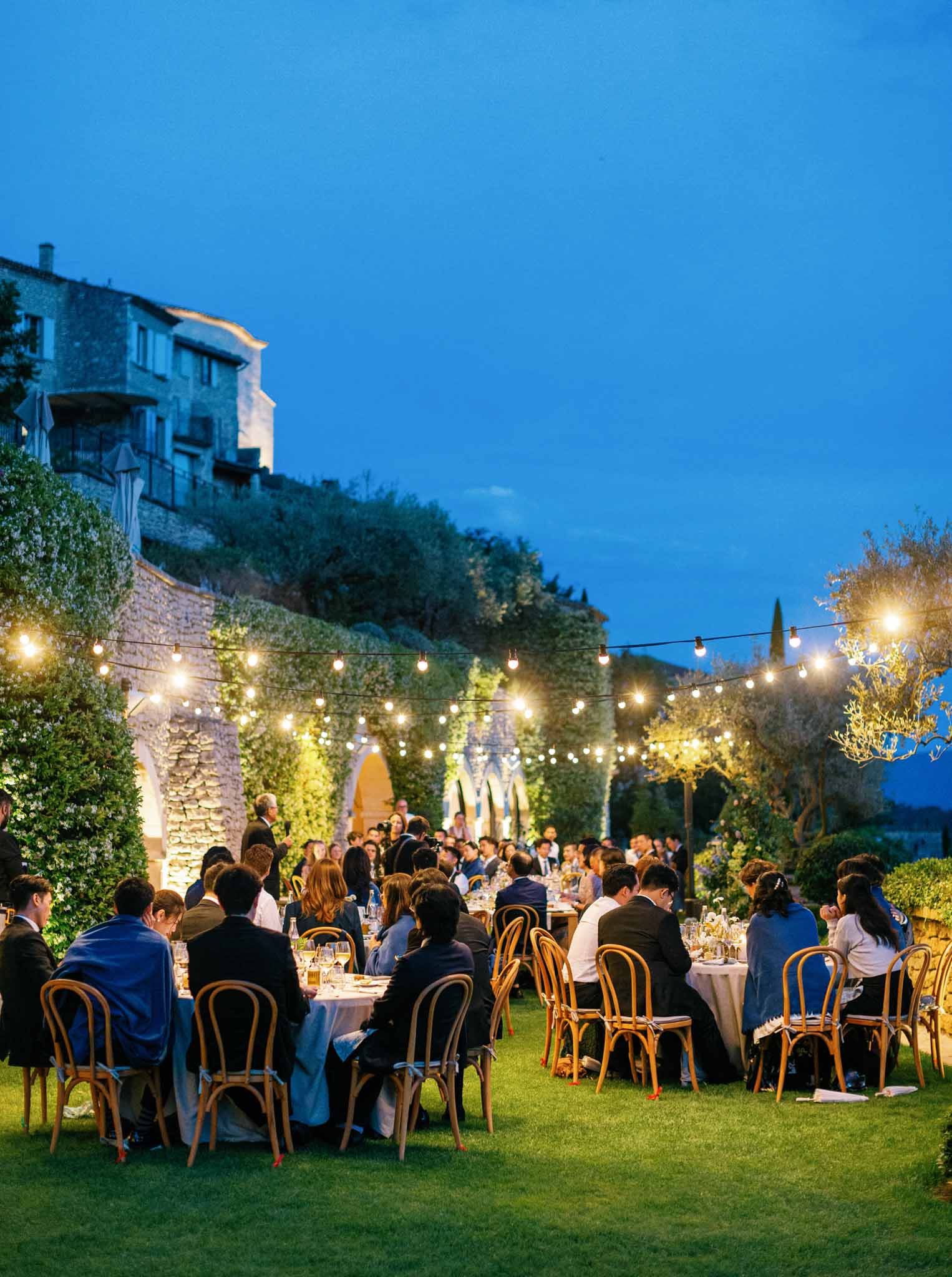 Evening outdoor reception with string lights on hillside garden terrace at Provencal venue