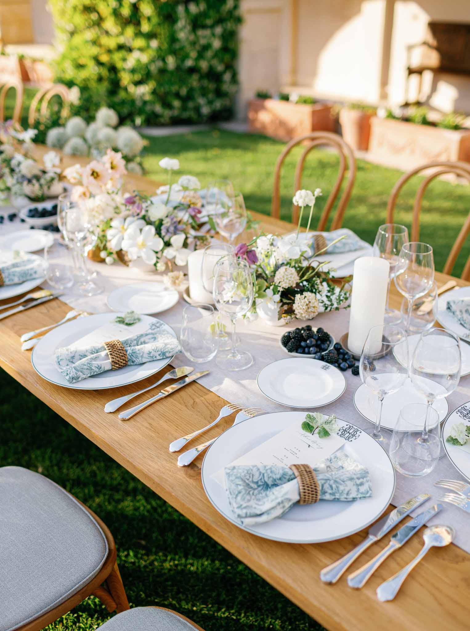 Outdoor garden reception table with blue toile napkins, gold flatware, and hydrangea centerpieces